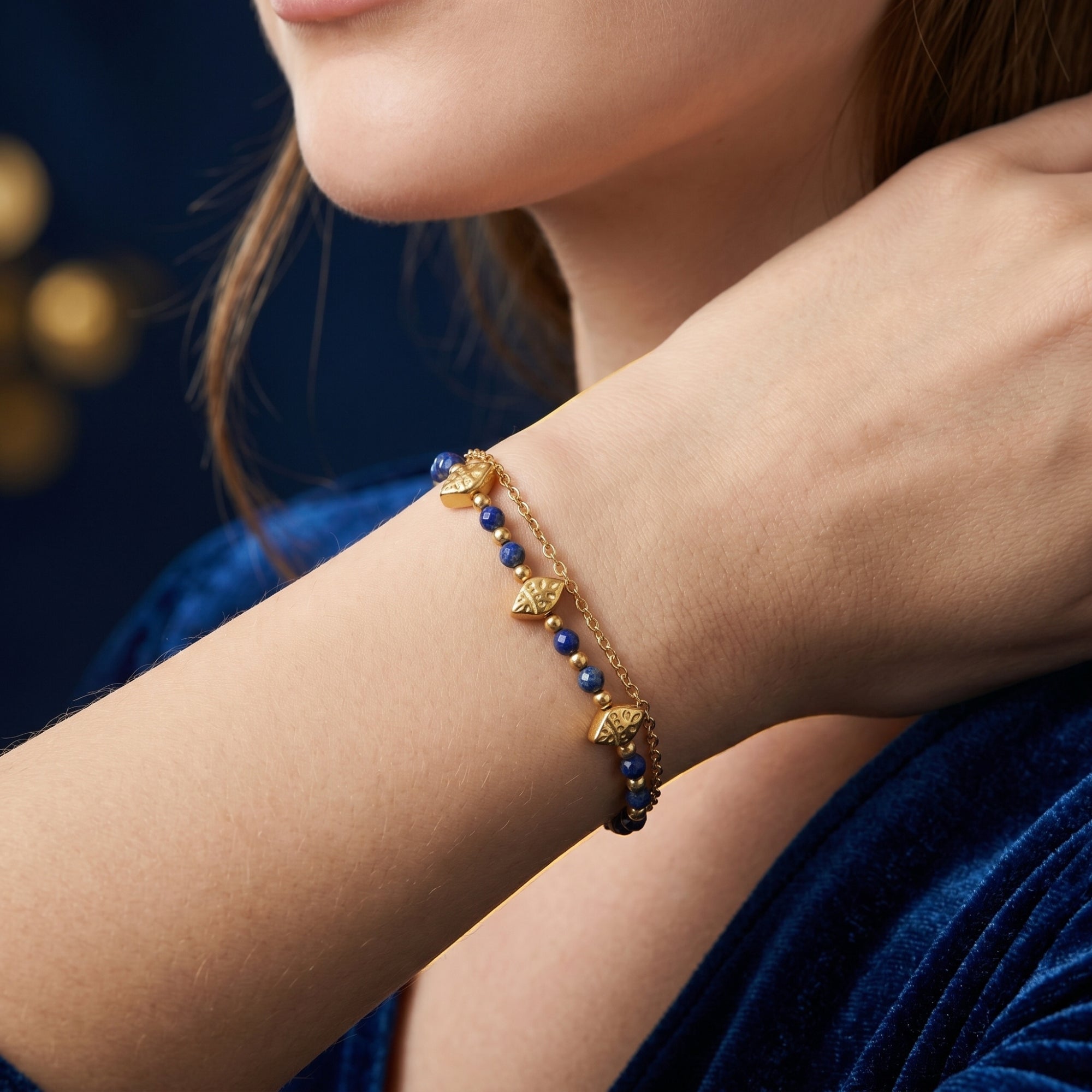 Woman wearing the 18k gold-plated lapis bead bracelet on her wrist, paired with a blue velvet dress.