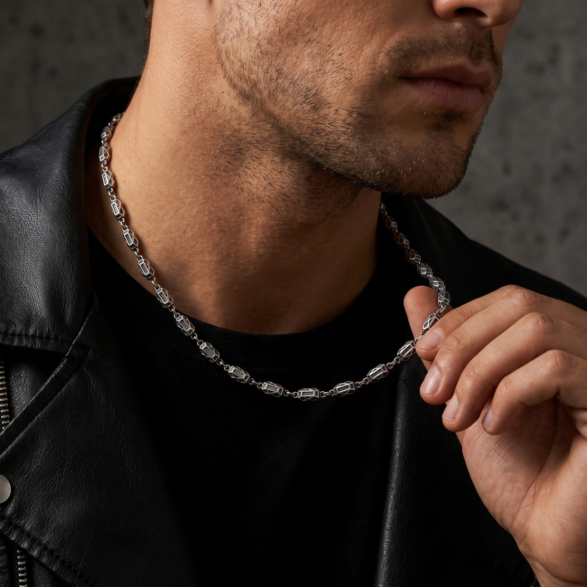 Man wearing the silver geometric link necklace with a black shirt and leather jacket.