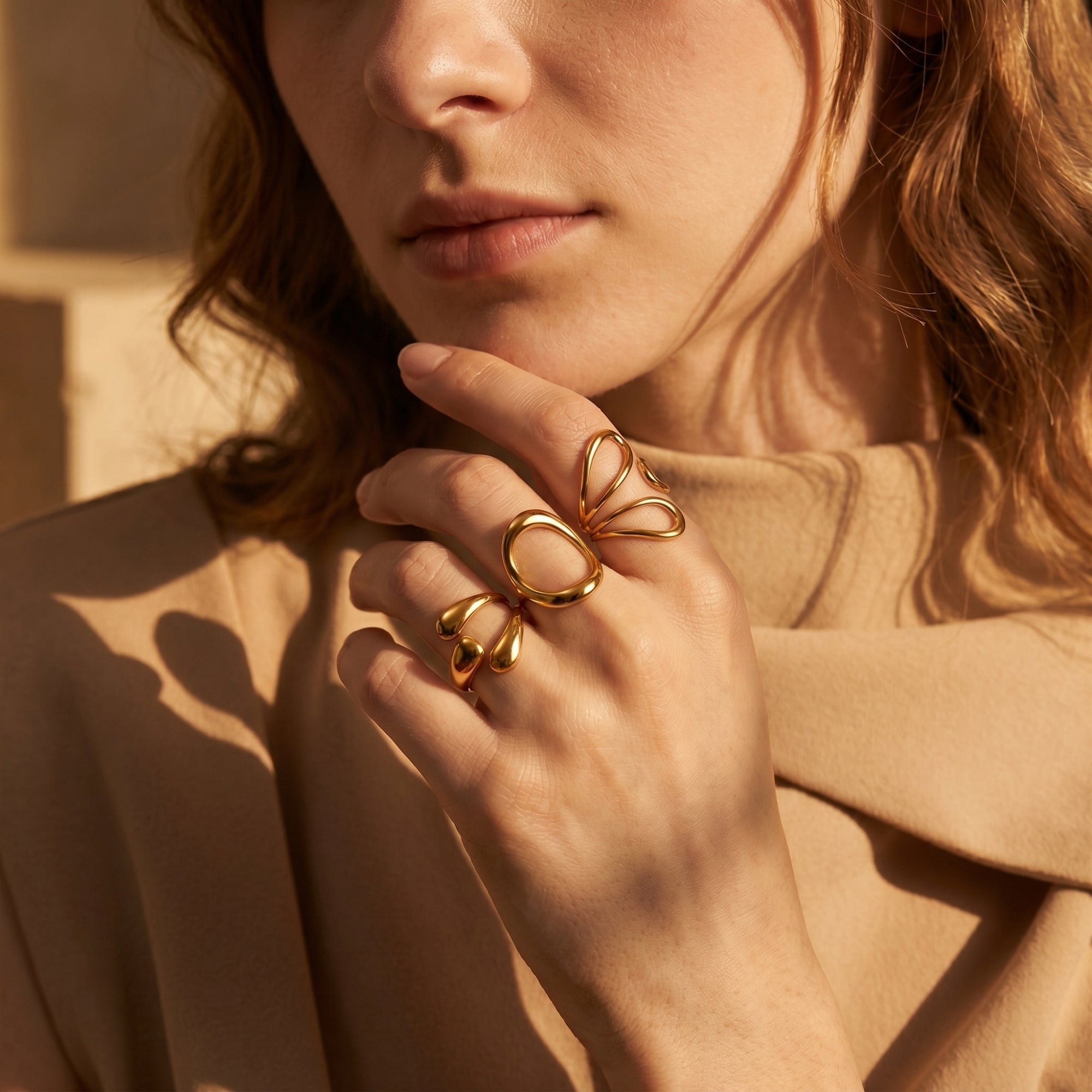 Model wearing three gold-finished molten rings on her hand.