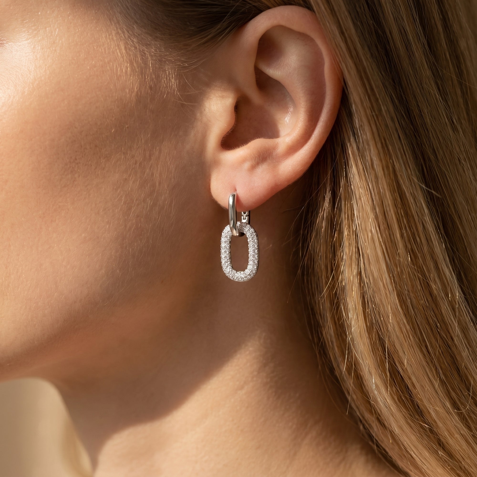 Silver moissanite double-link drop earring worn on a model's ear.