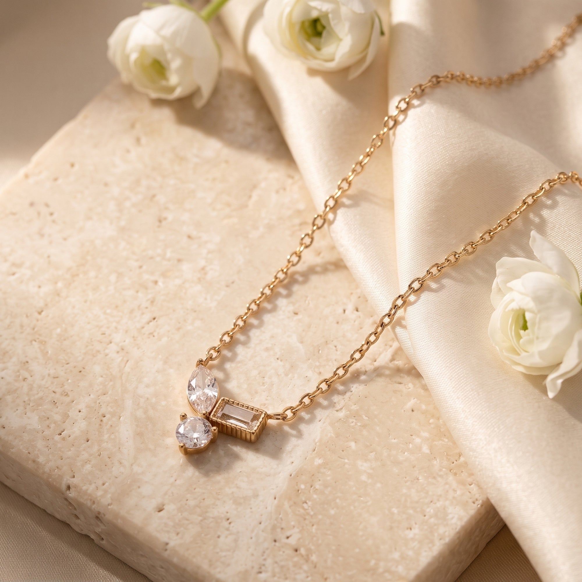 Detail of 18K gold necklace pendant featuring marquise, baguette, and round brilliant cubic zirconia stones.