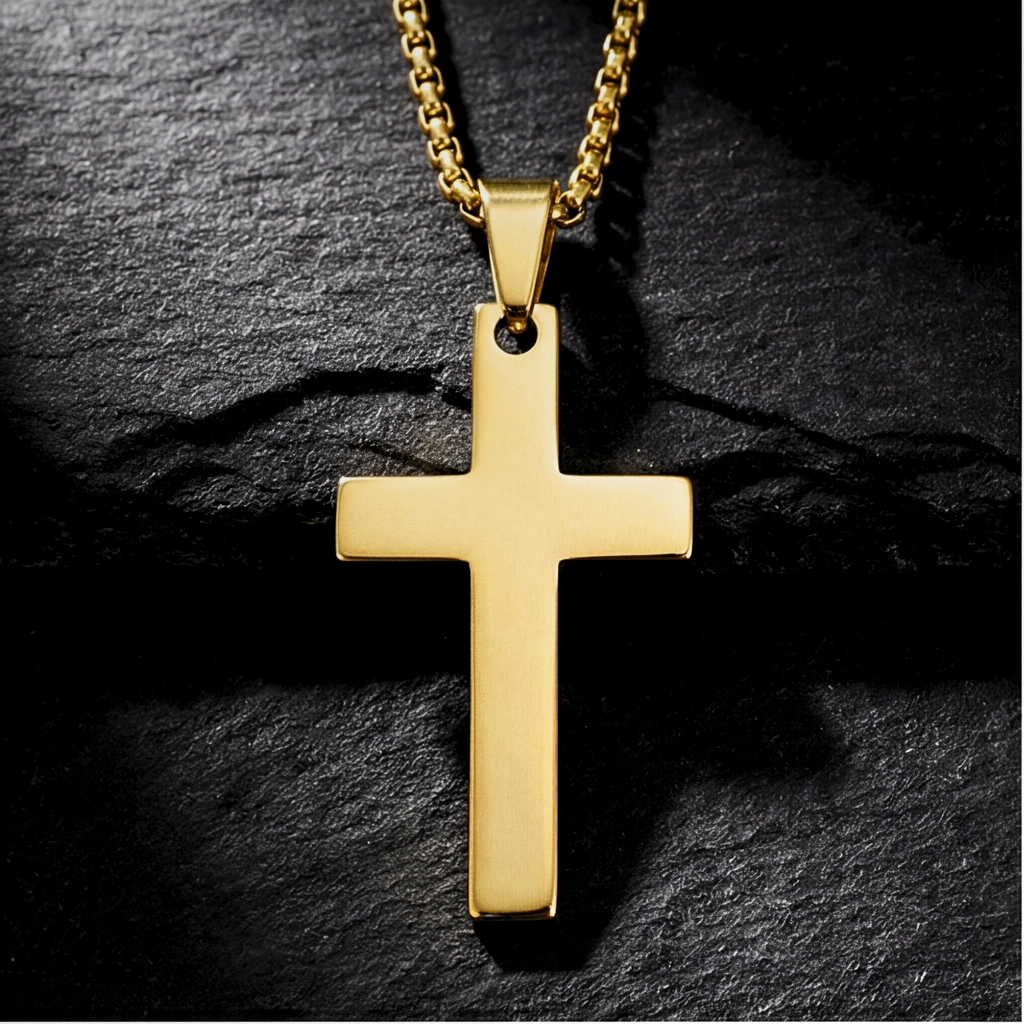 Close-up view of the gold stainless steel Apostle Cross pendant and box chain on a dark stone background.