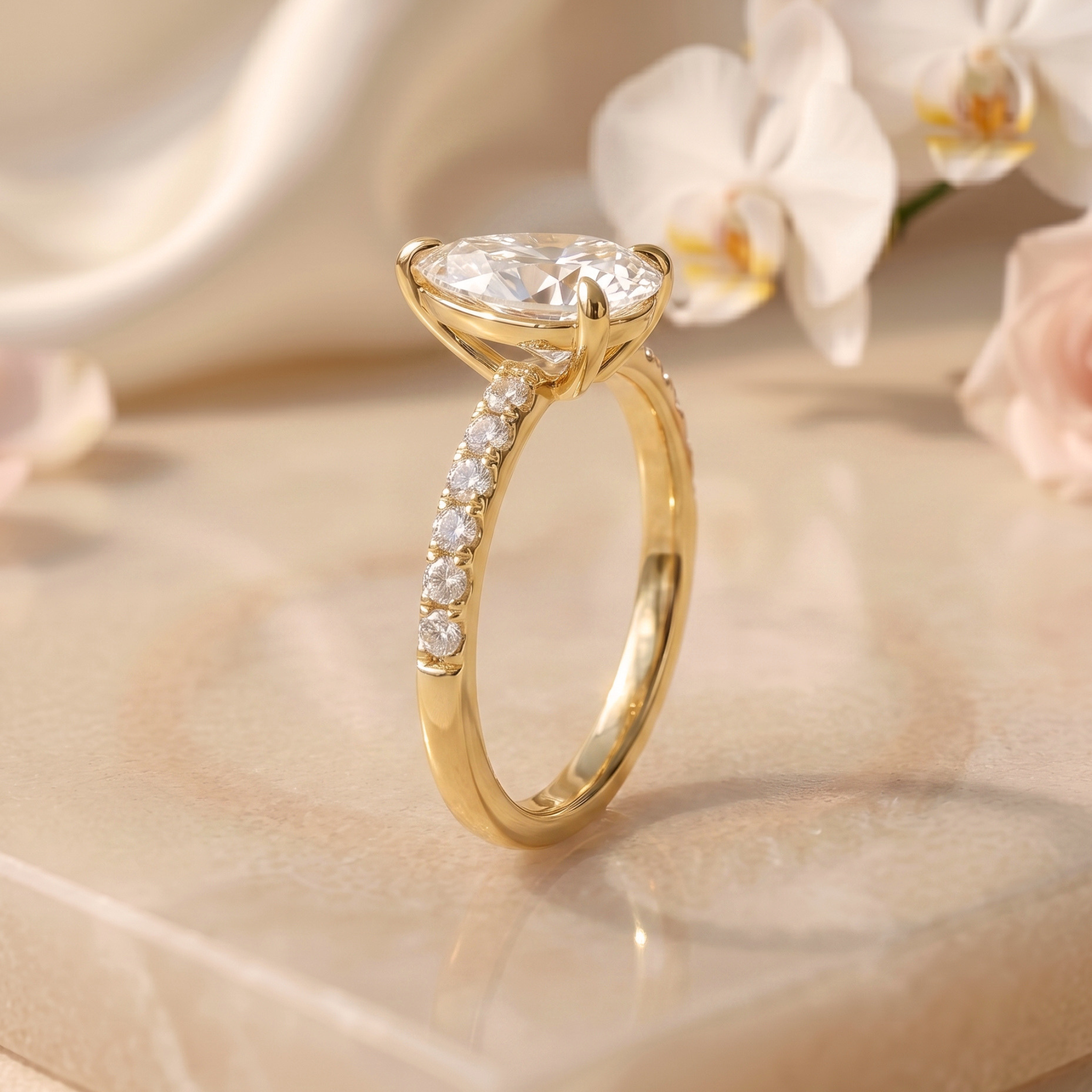 A detailed profile view of a yellow gold pear-cut moissanite ring showing the elegant side setting and pavé band.