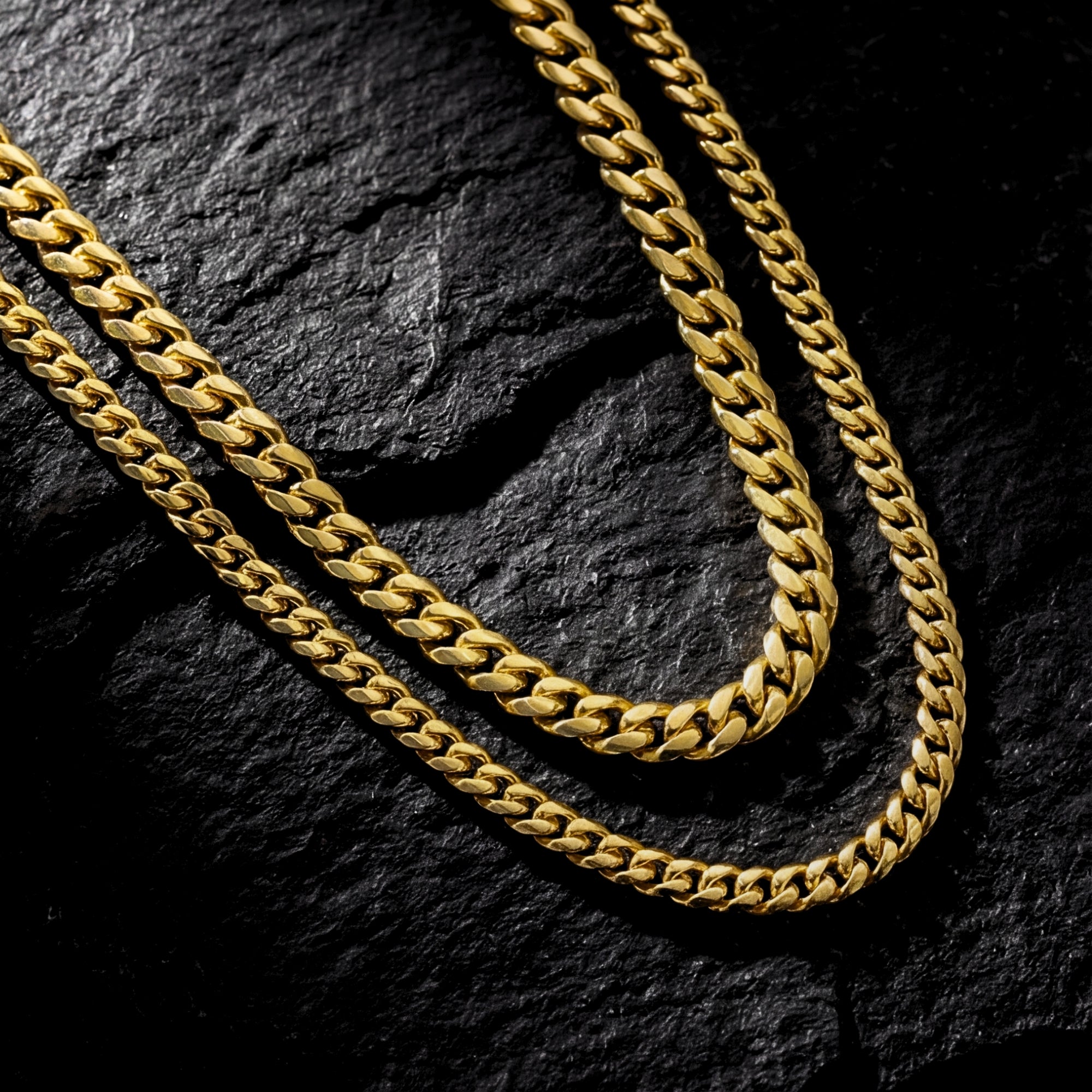 Macro view of the interlocking links on two gold-coated stainless steel Cuban chains.