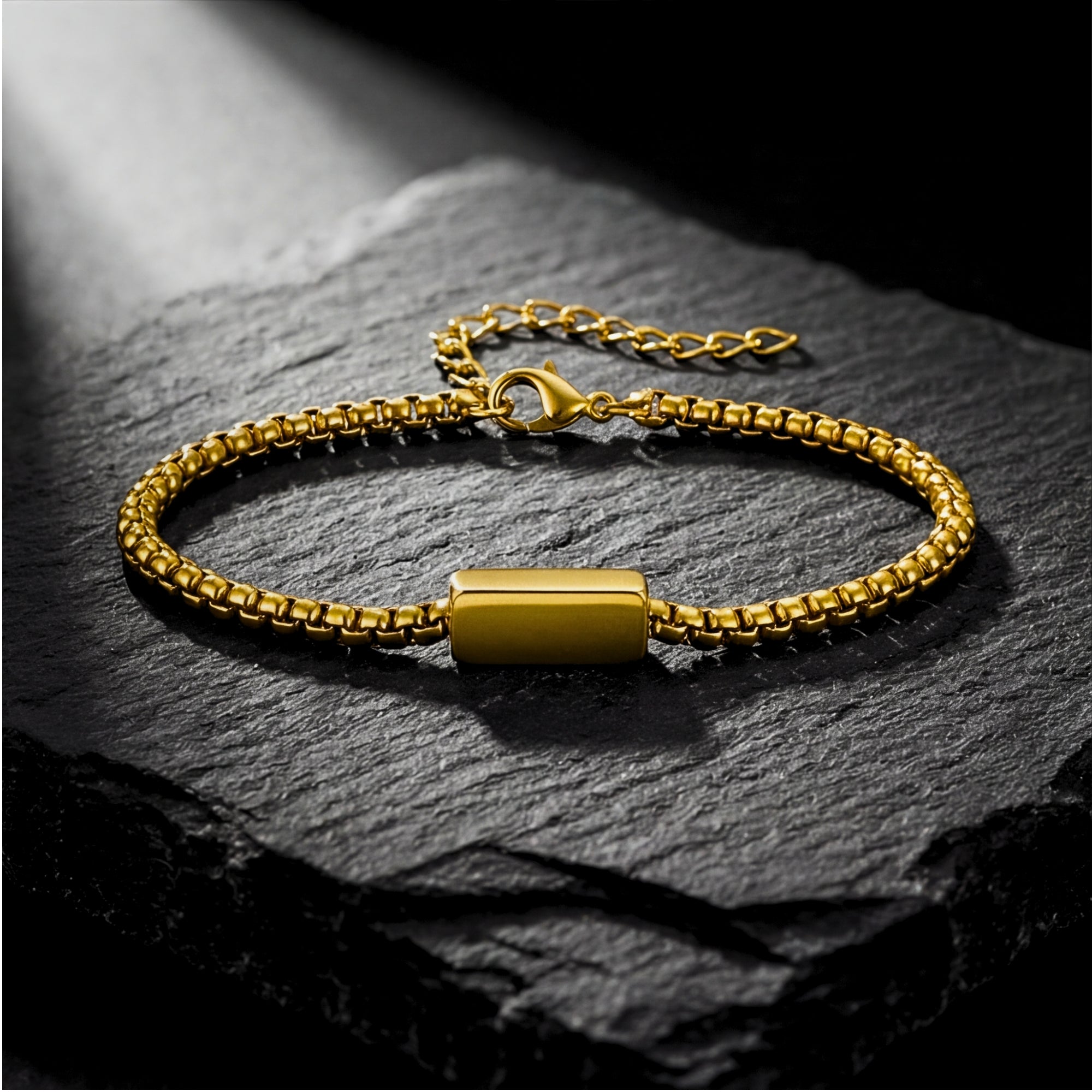 Gold stainless steel 5mm Cipher ID bracelet with lobster clasp displayed on a black rock surface.