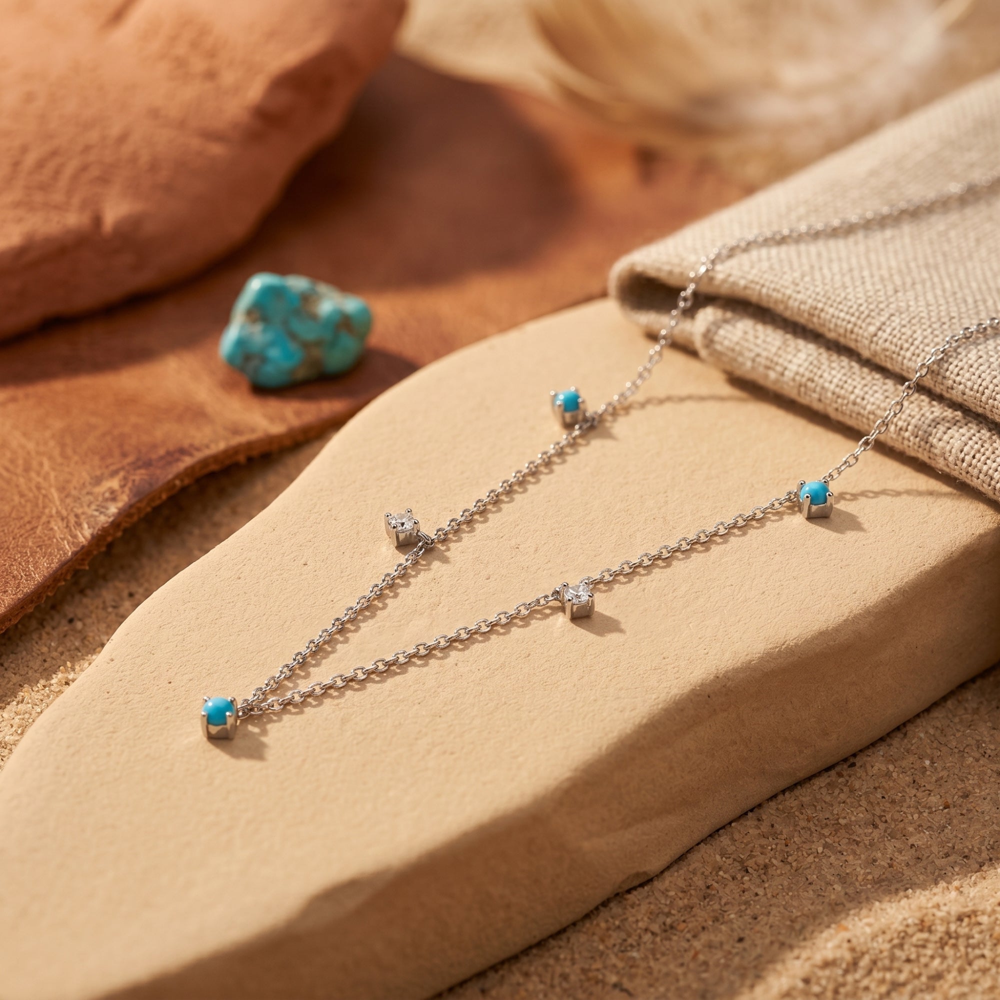 Close-up of silver chain necklace featuring round turquoise beads and clear star-shaped accents on a stone.