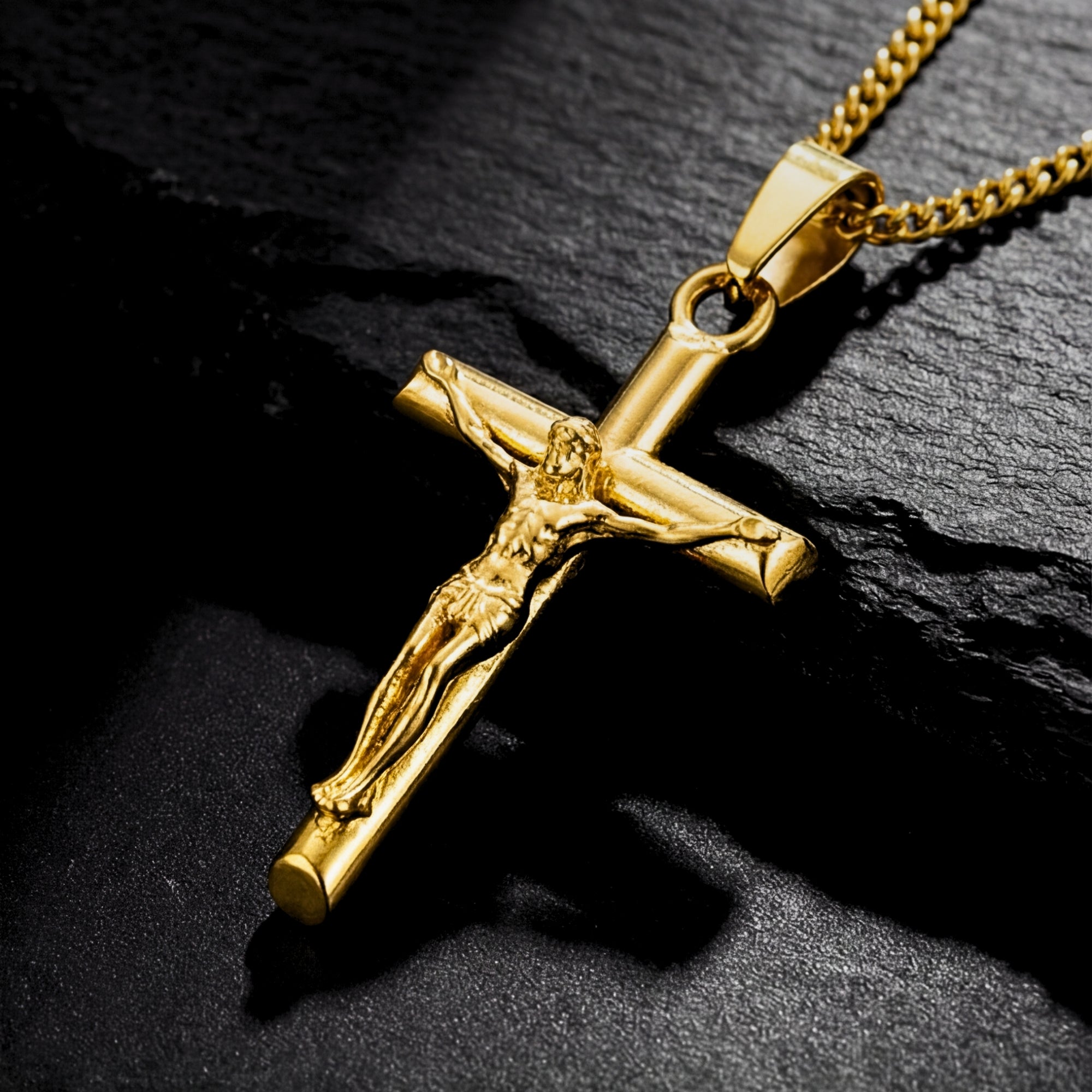 Macro view of the gold stainless steel crucifix pendant detailing the figure of Jesus on a dark background.