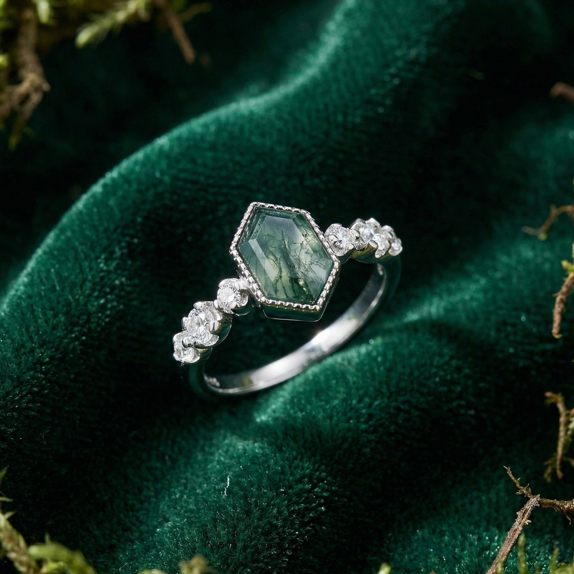 Sterling silver kite cut moss agate ring with diamond accents on a green velvet background.