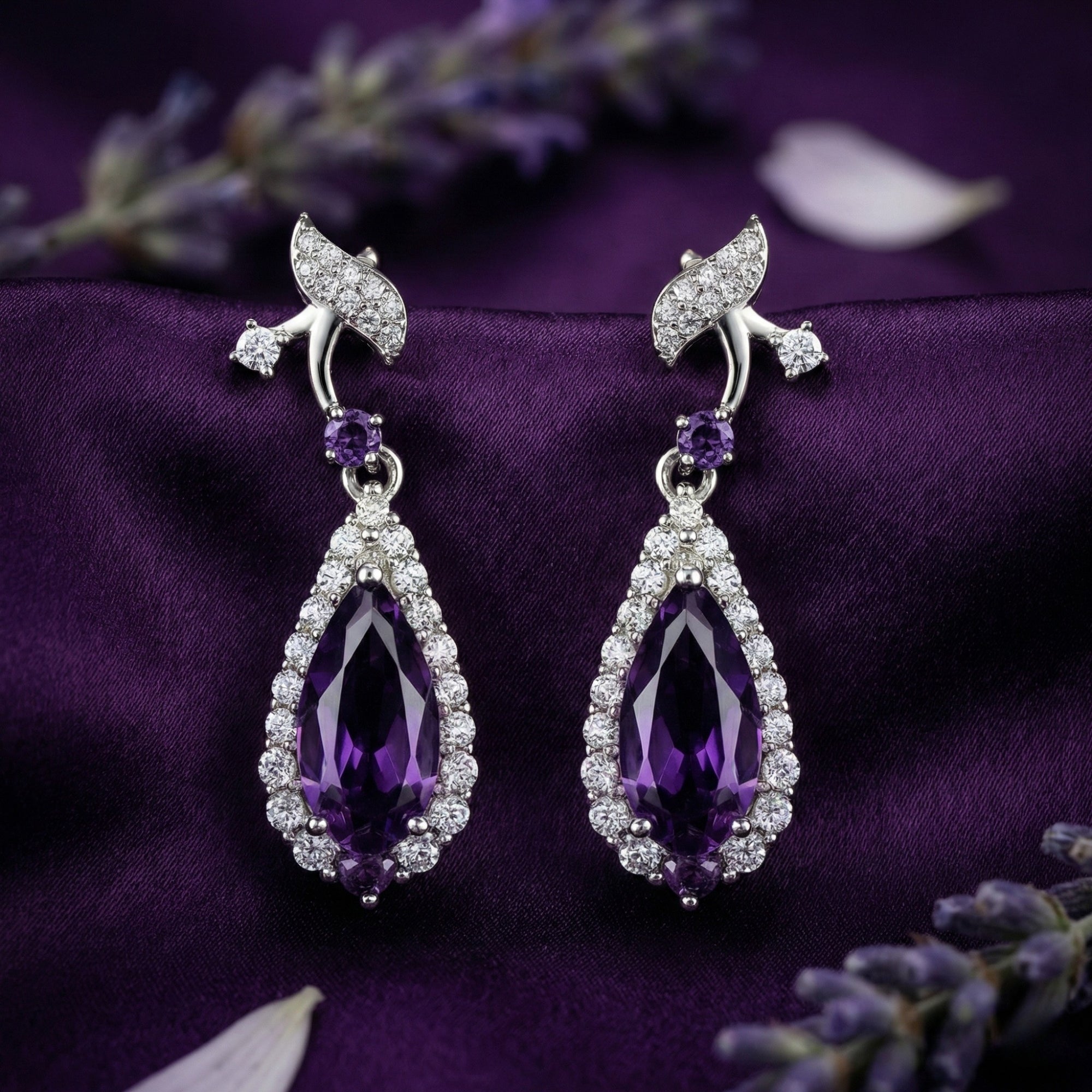 Detailed view of pear cut amethyst drop earrings in S925 sterling silver on purple fabric.