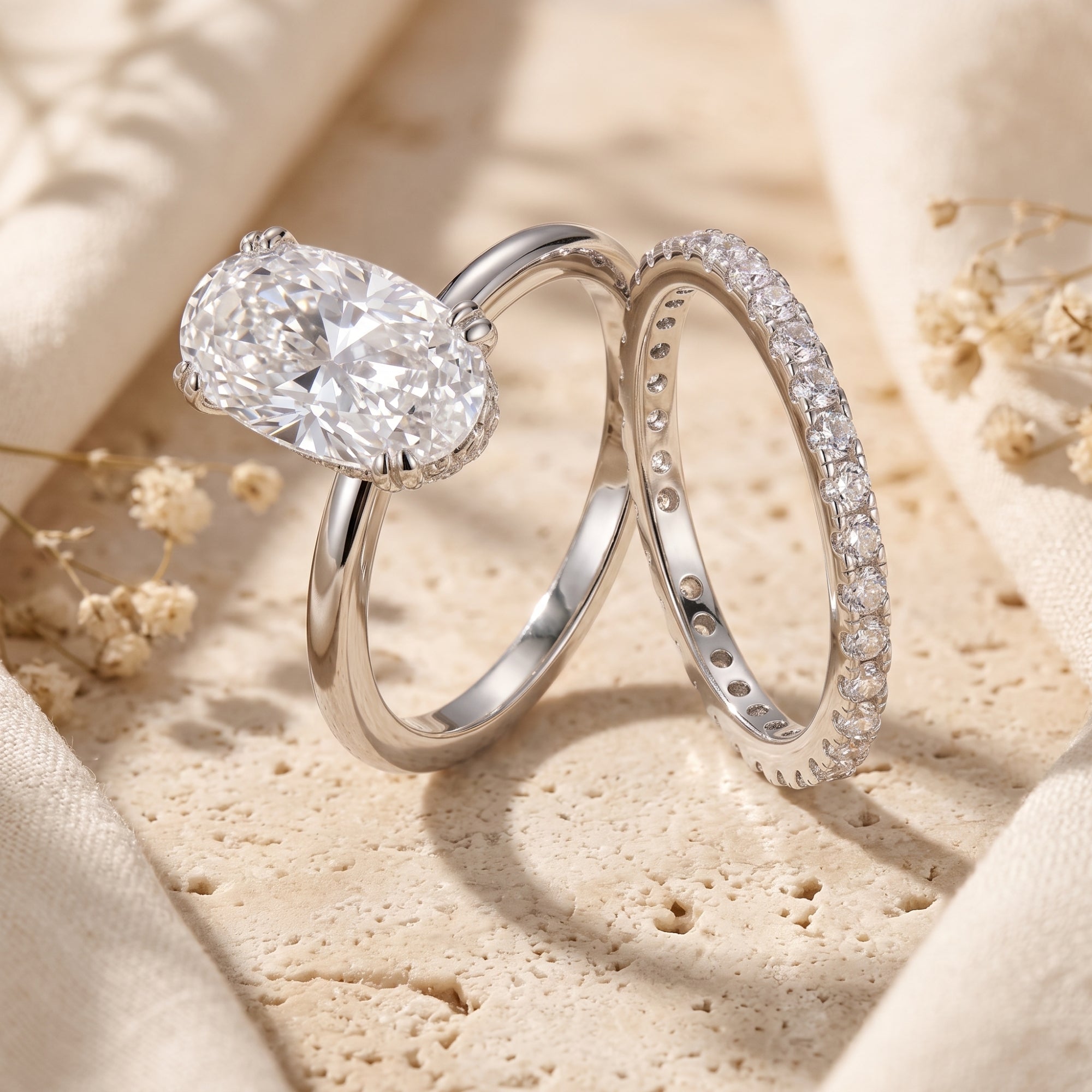 Close-up of oval-cut zircon ring and silver eternity band on textured stone.