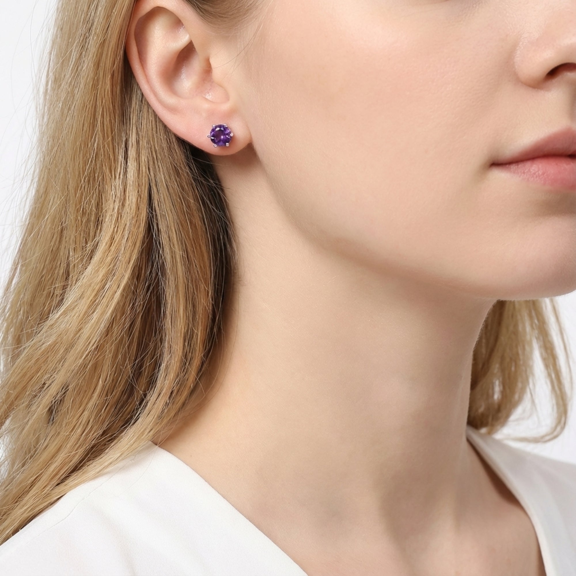 Woman wearing a 6.5mm round cut simulated amethyst stud earring in S925 sterling silver.