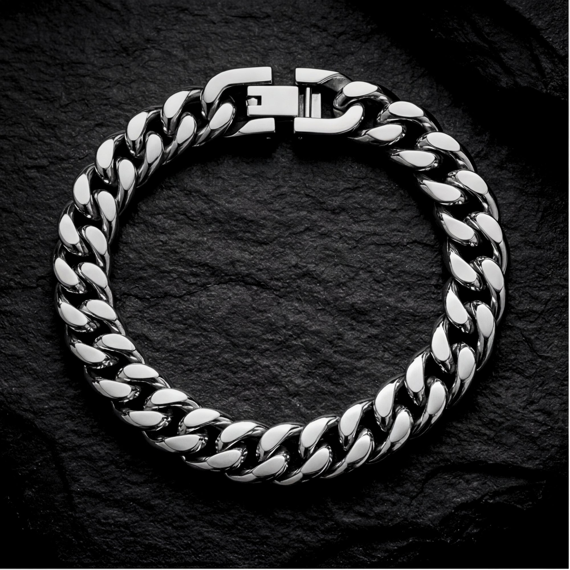 Top-down view of a men's silver stainless steel Cuban link bracelet on a dark slate surface.