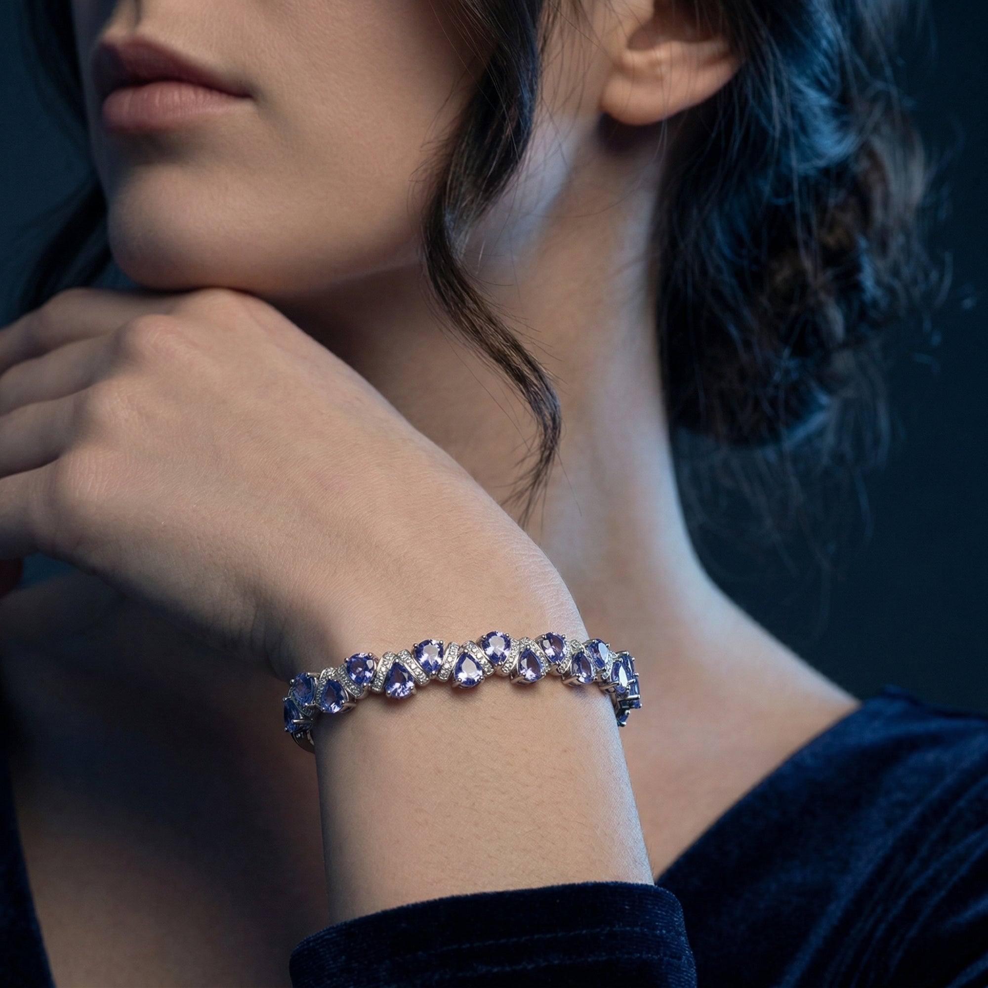 Close-up of the pear-cut tanzanite tennis bracelet in white gold worn on a model's wrist.