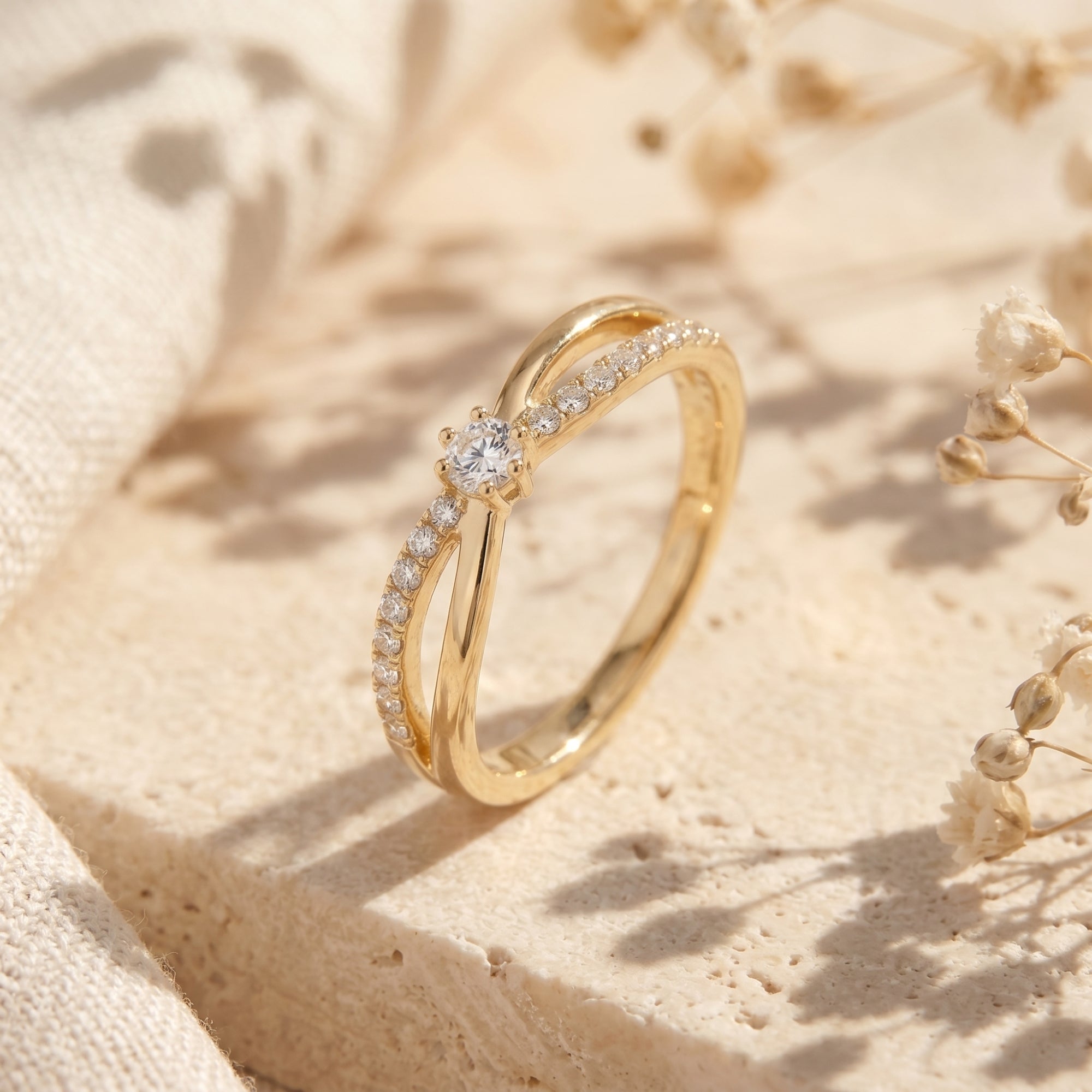 Angled view of a gold bypass moissanite ring on stone.