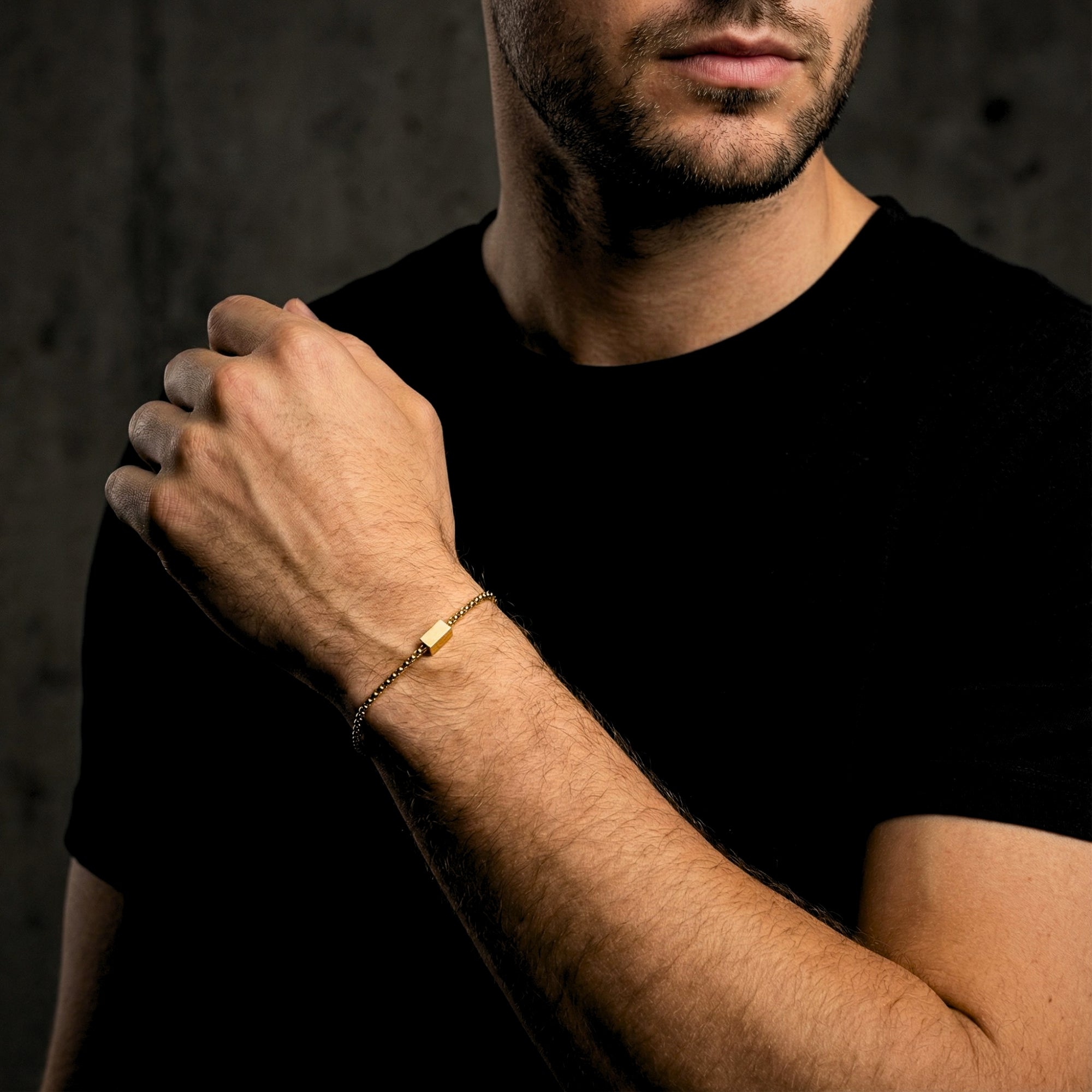 Model wearing the gold stainless steel 5mm Cipher ID bracelet on his wrist, paired with a black shirt.