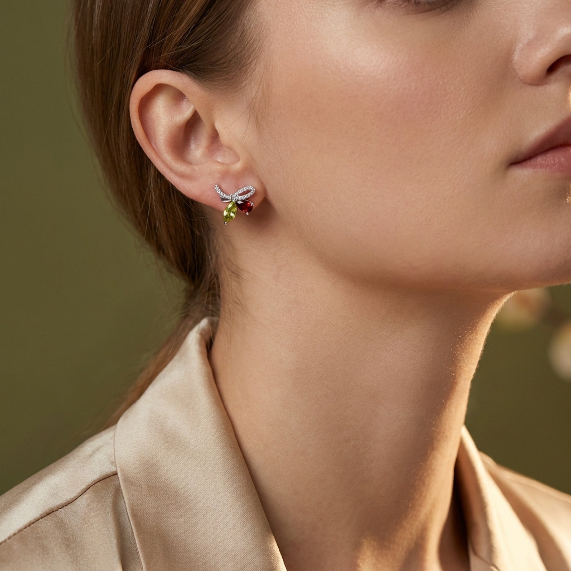 Profile view of a woman wearing the Giselle Marquise sterling silver bow earrings with green and red gemstones.