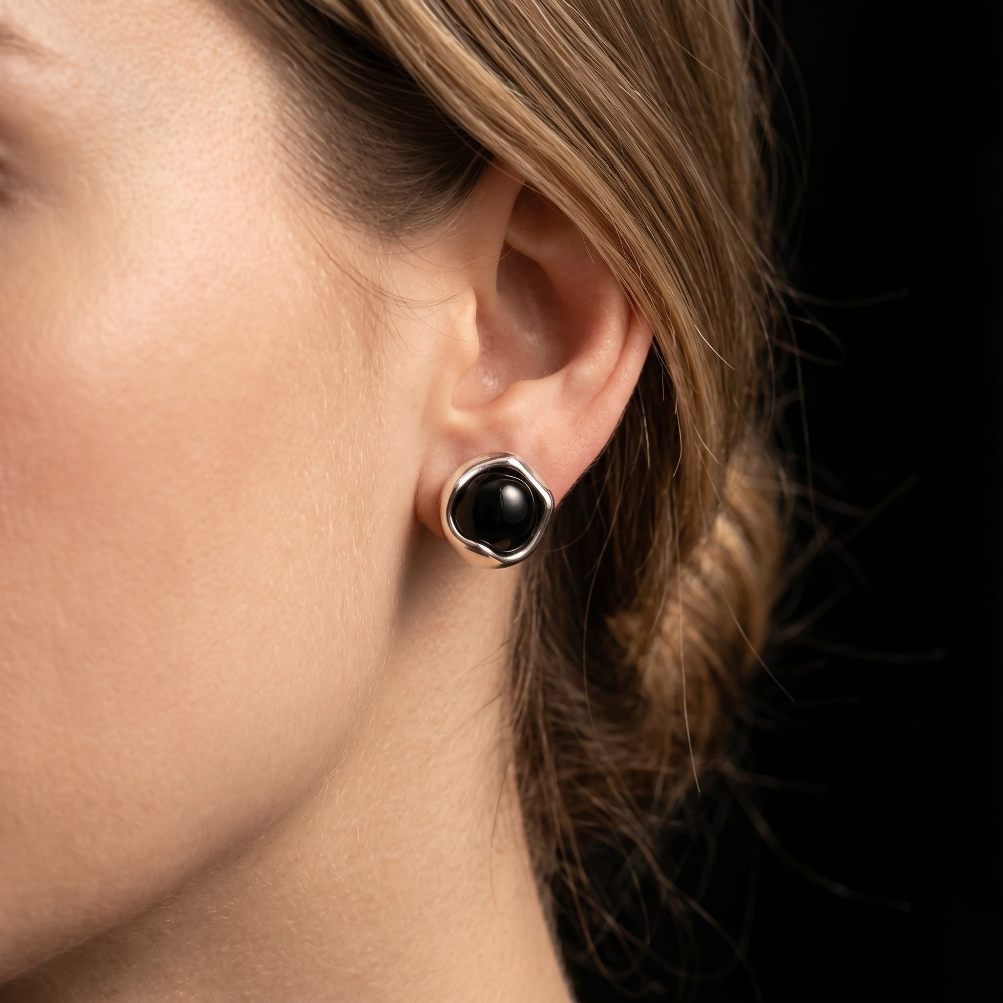 Profile view of a woman wearing the Eclipsa round black onyx earring in a silver setting.