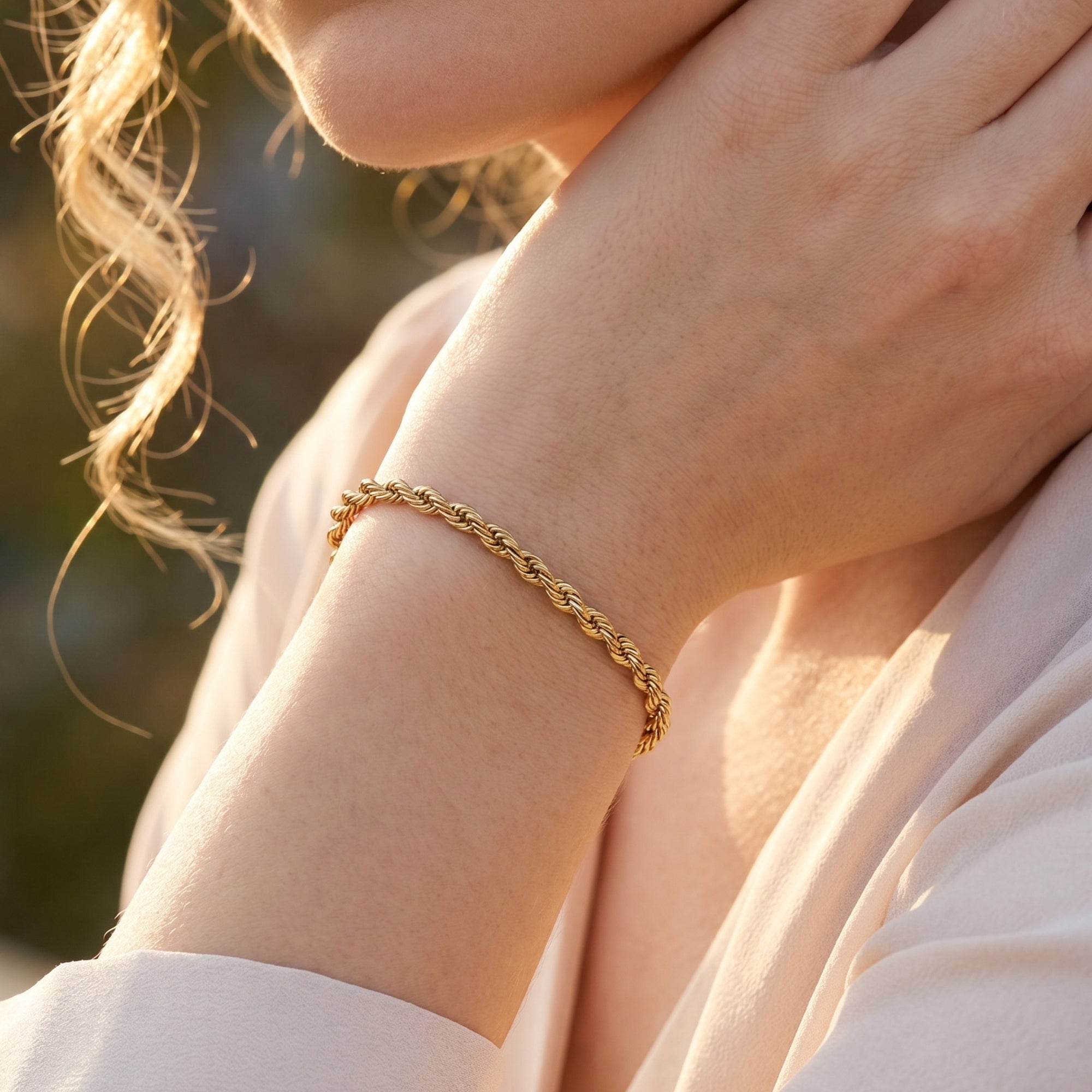Thick gold rope chain bracelet on a model's wrist in warm natural light.