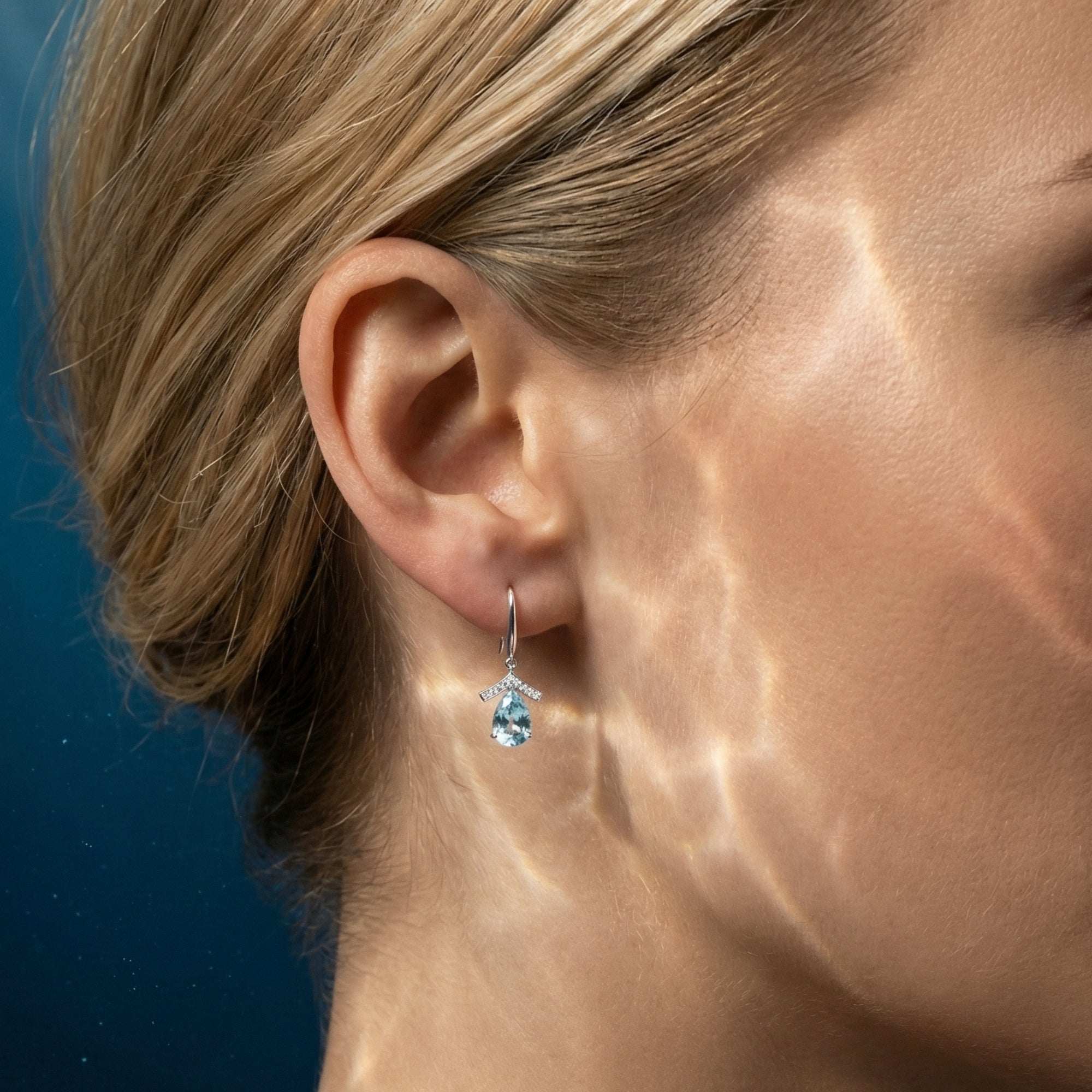 Side view of a woman wearing the Serenata pear cut natural aquamarine drop earring in platinum.