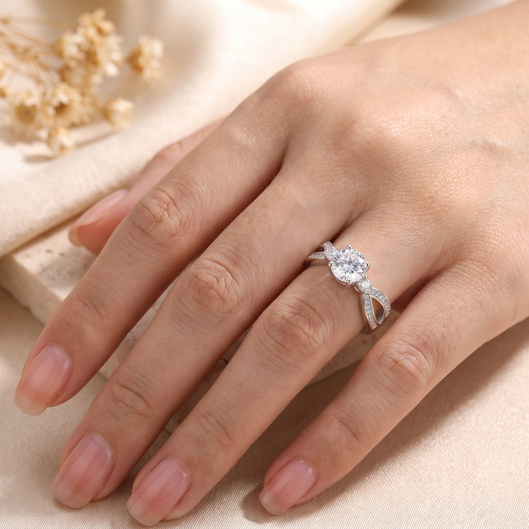 Top-down view of the Noeline round cut simulated diamond promise ring in sterling silver on a model's finger.