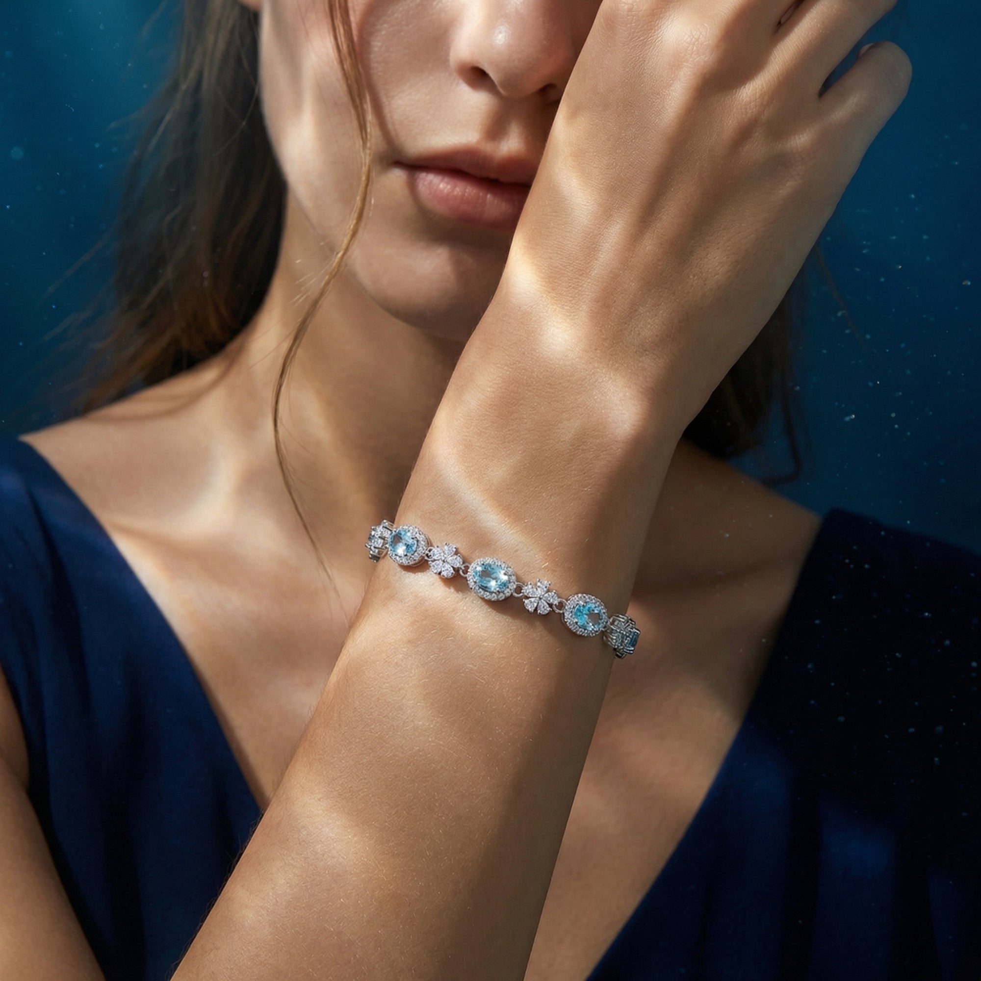 March birthstone aquamarine station bracelet in sterling silver displayed on a woman's wrist.