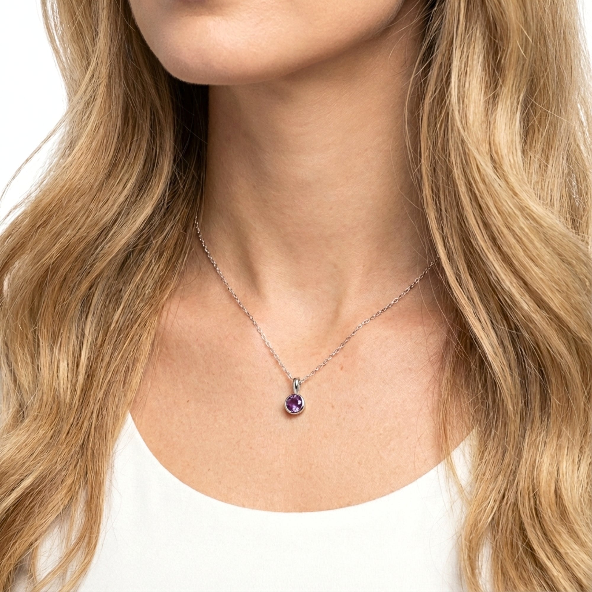Sterling silver necklace with a round cut deep royal purple simulated amethyst pendant worn by a model.