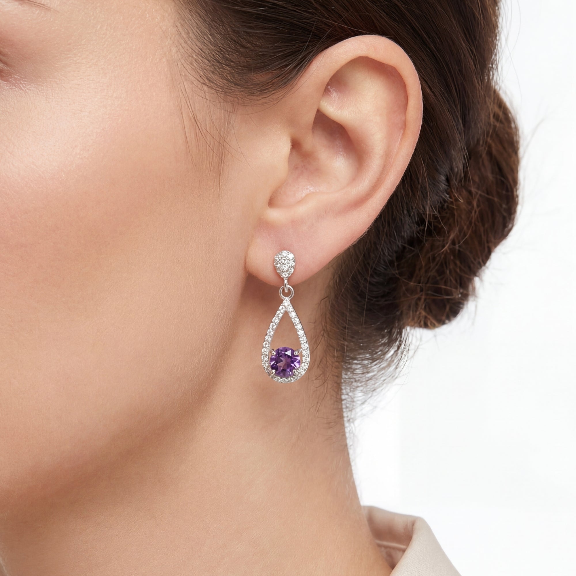 Close-up of a sterling silver simulated amethyst teardrop earring worn on a model's ear.