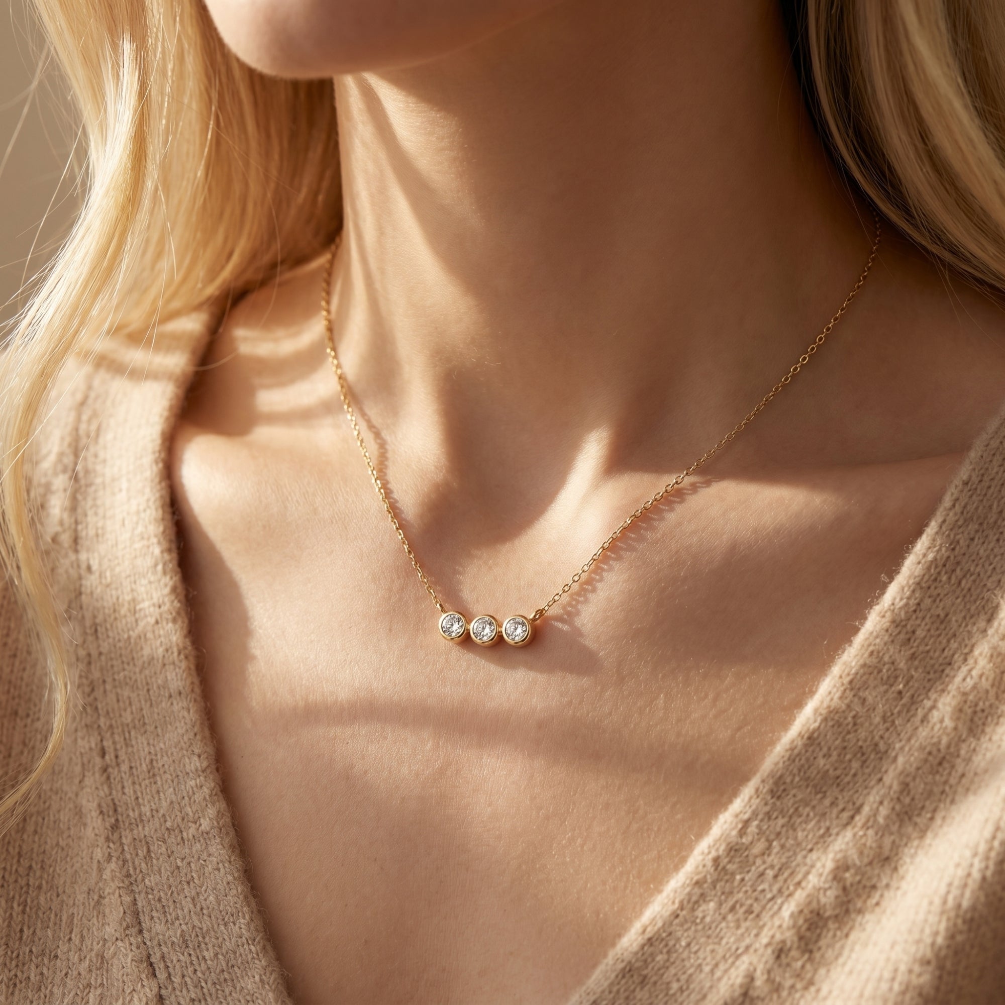 Model wearing the yellow gold three-stone moissanite bezel pendant necklace.