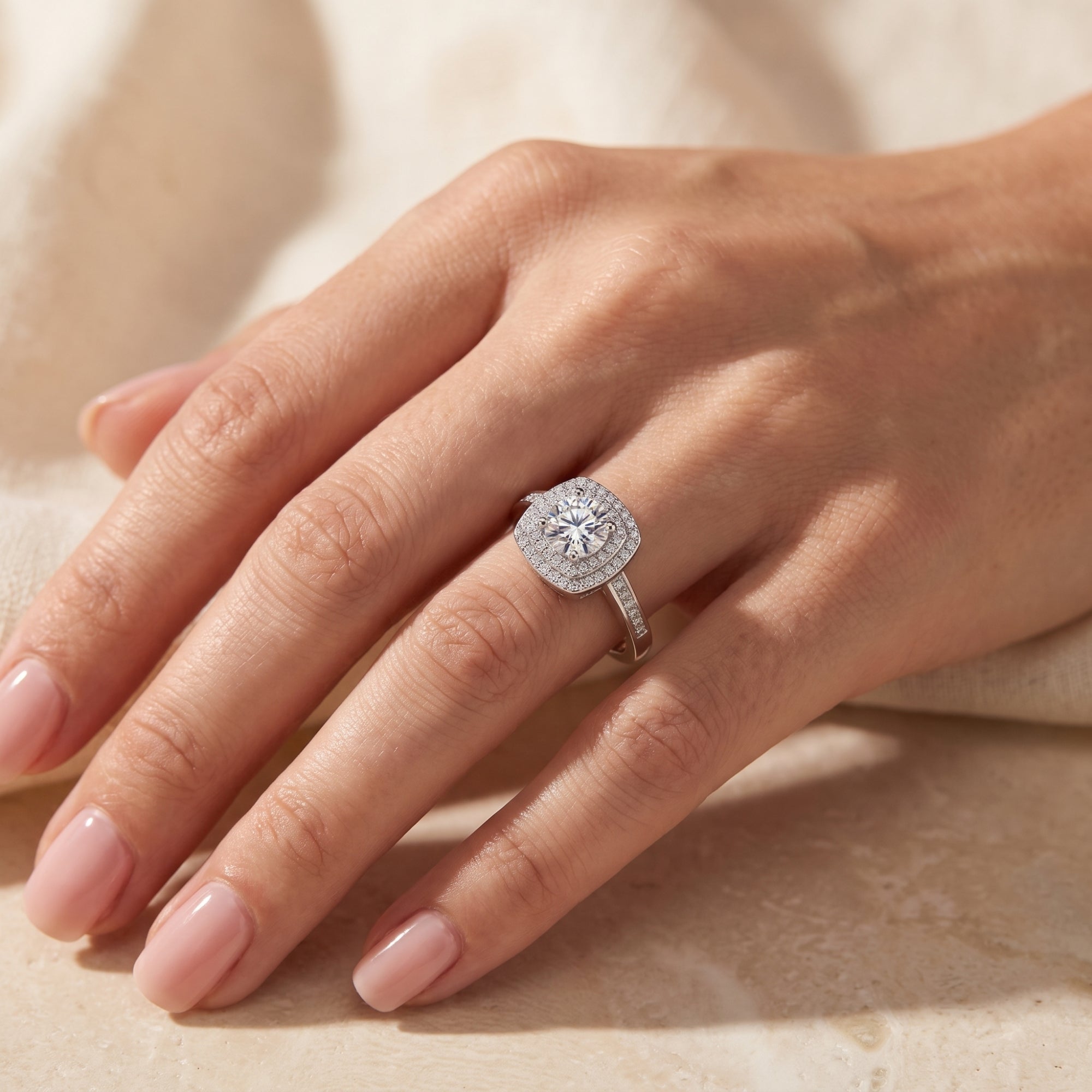 Sterling silver Juliette ring with round simulated diamond and double halo on a woman's finger.