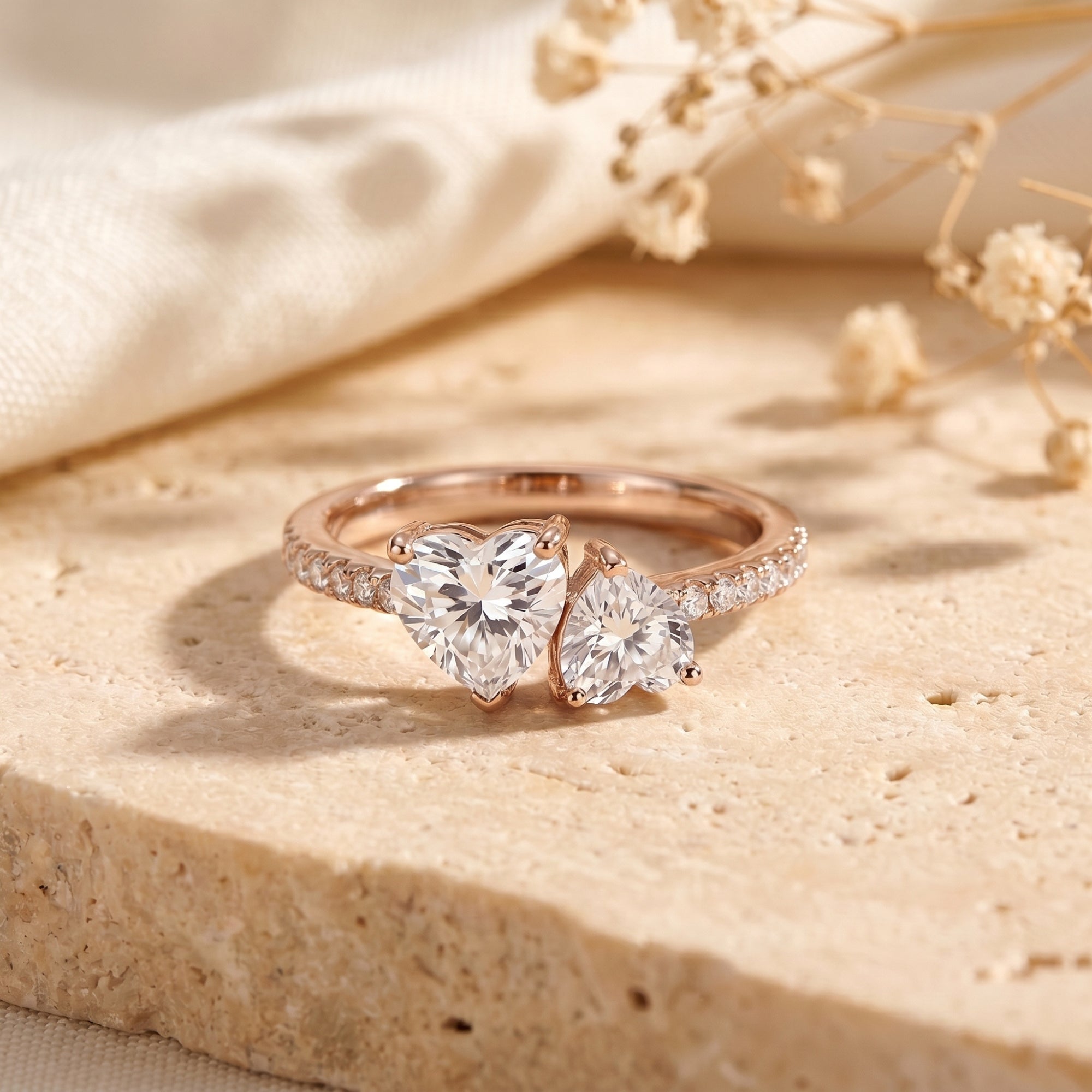 Rose gold Toi et Moi ring featuring two heart-cut moissanite stones on a textured background.