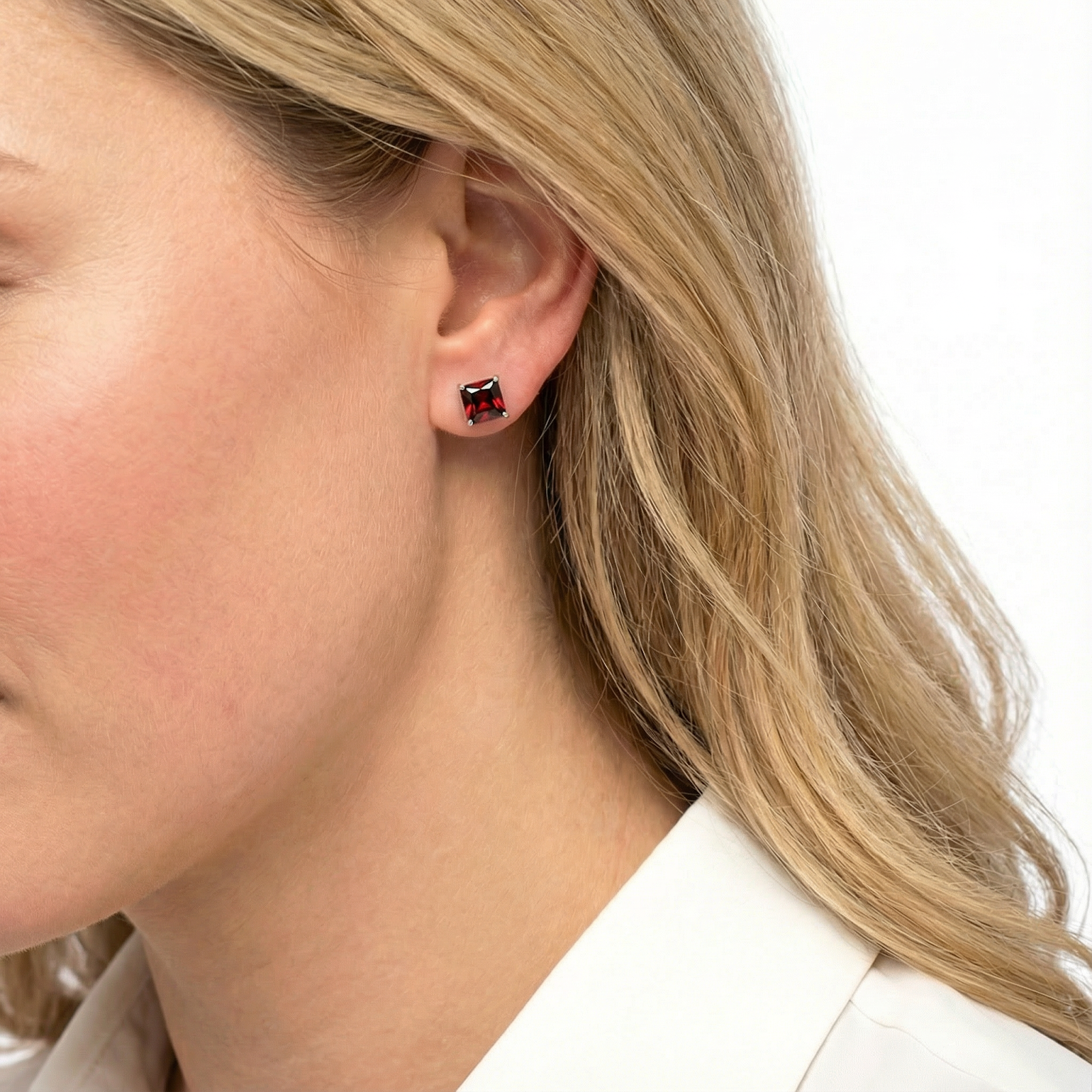 Side profile of a model wearing a square emerald cut red garnet earring in rose gold vermeil.