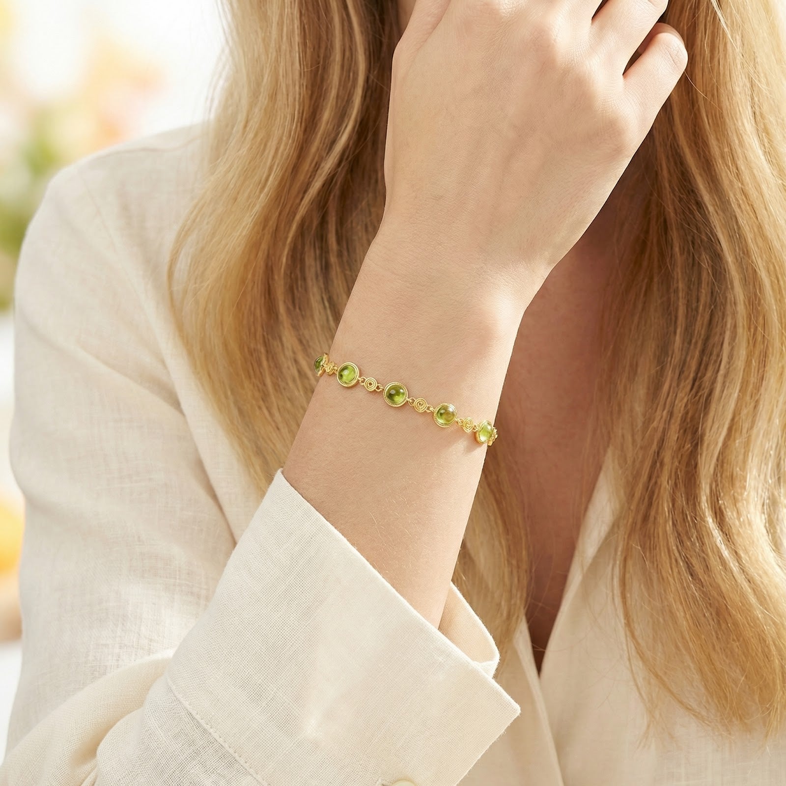 August birthstone station bracelet in 18K gold vermeil with simulated peridot stones worn on a woman's wrist.