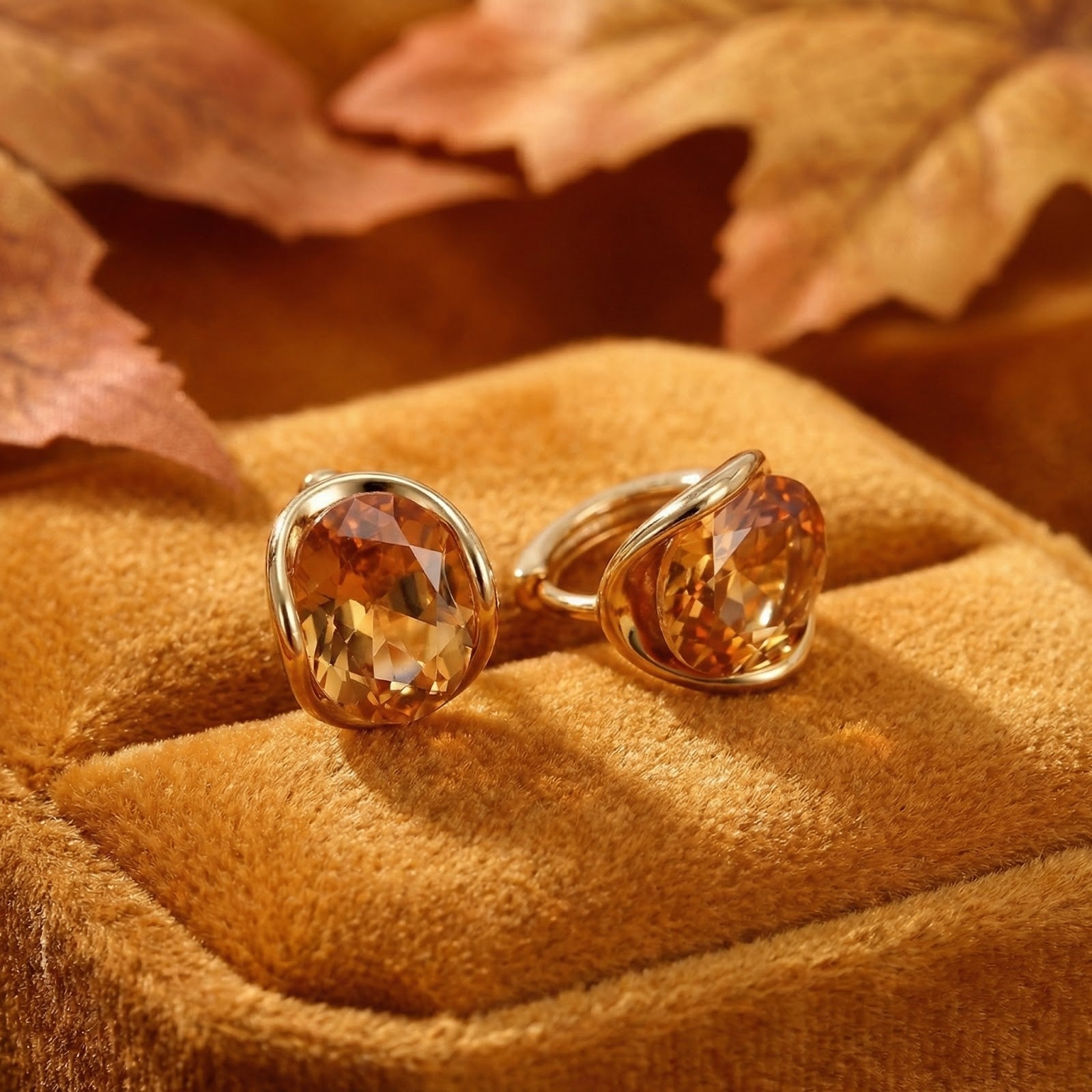 Oval honeyed simulated topaz stud earrings in 18K gold vermeil on a velvet surface with autumn leaves.