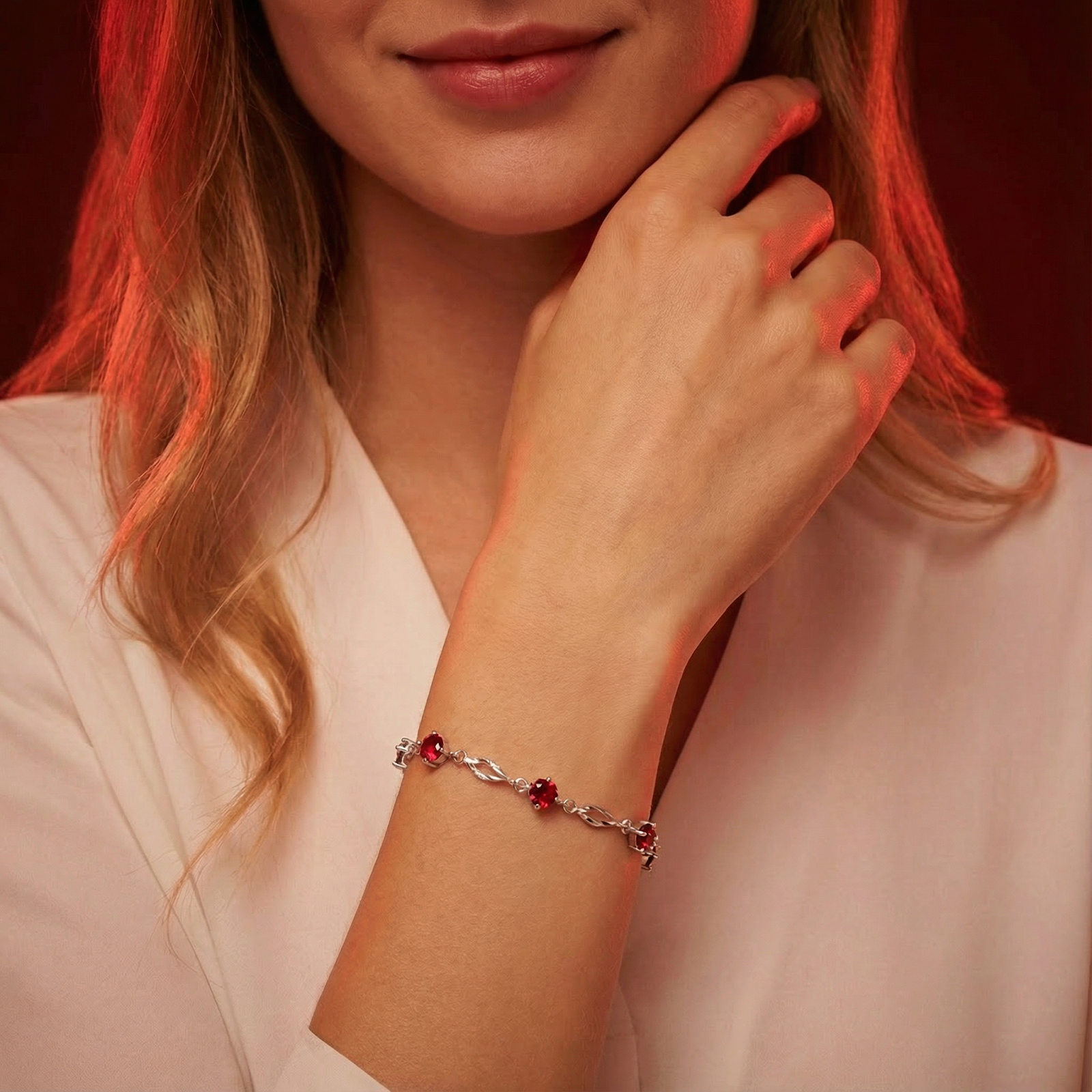 Woman wearing the Aderyn sterling silver station bracelet with red simulated rubies on her wrist.