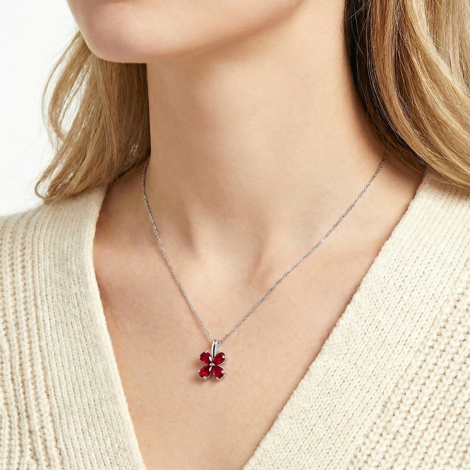 Woman wearing the Serenara Blossom sterling silver necklace with a red simulated ruby floral pendant.