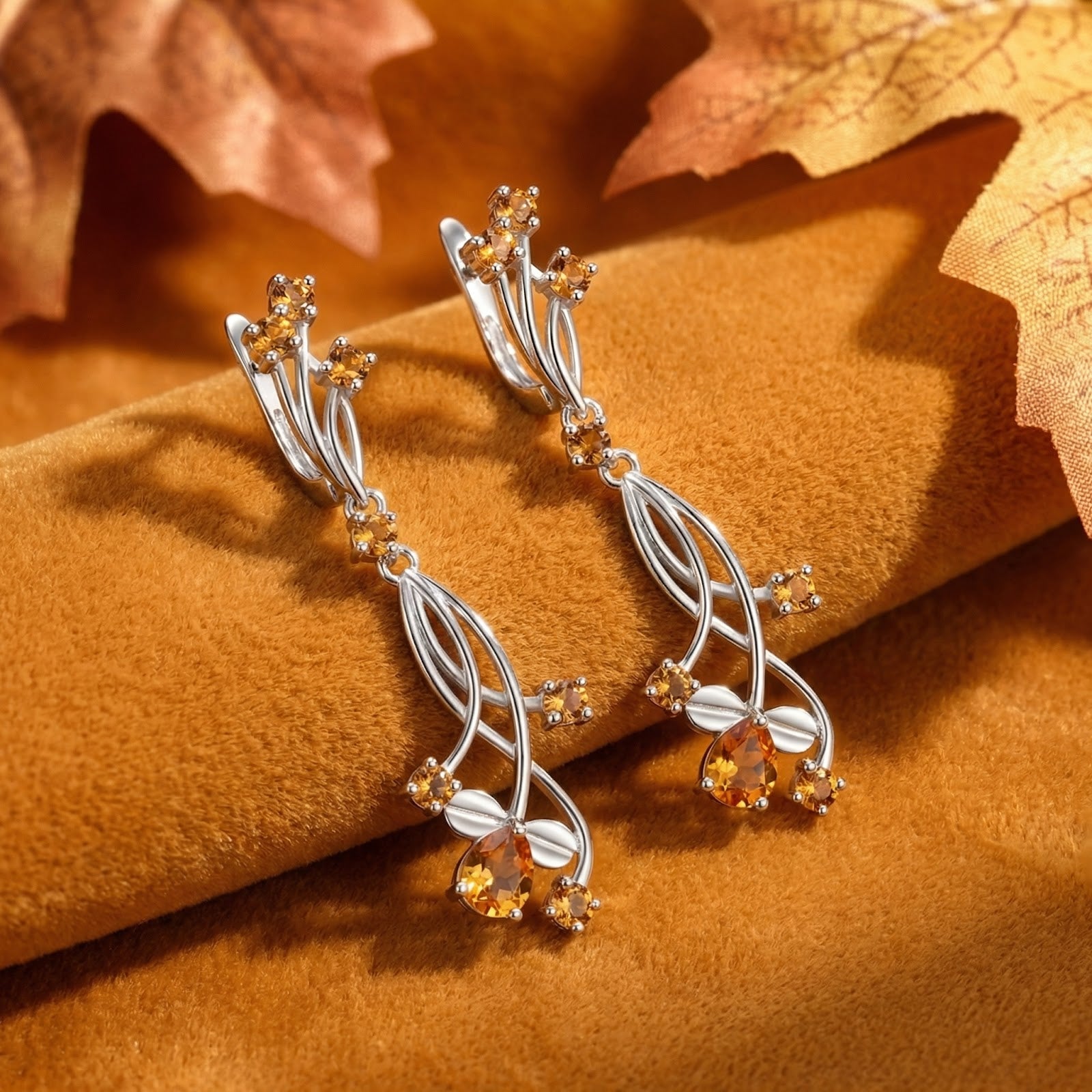 Sterling silver vine drop earrings with pear-cut simulated topaz stones on brown velvet with autumn leaves.