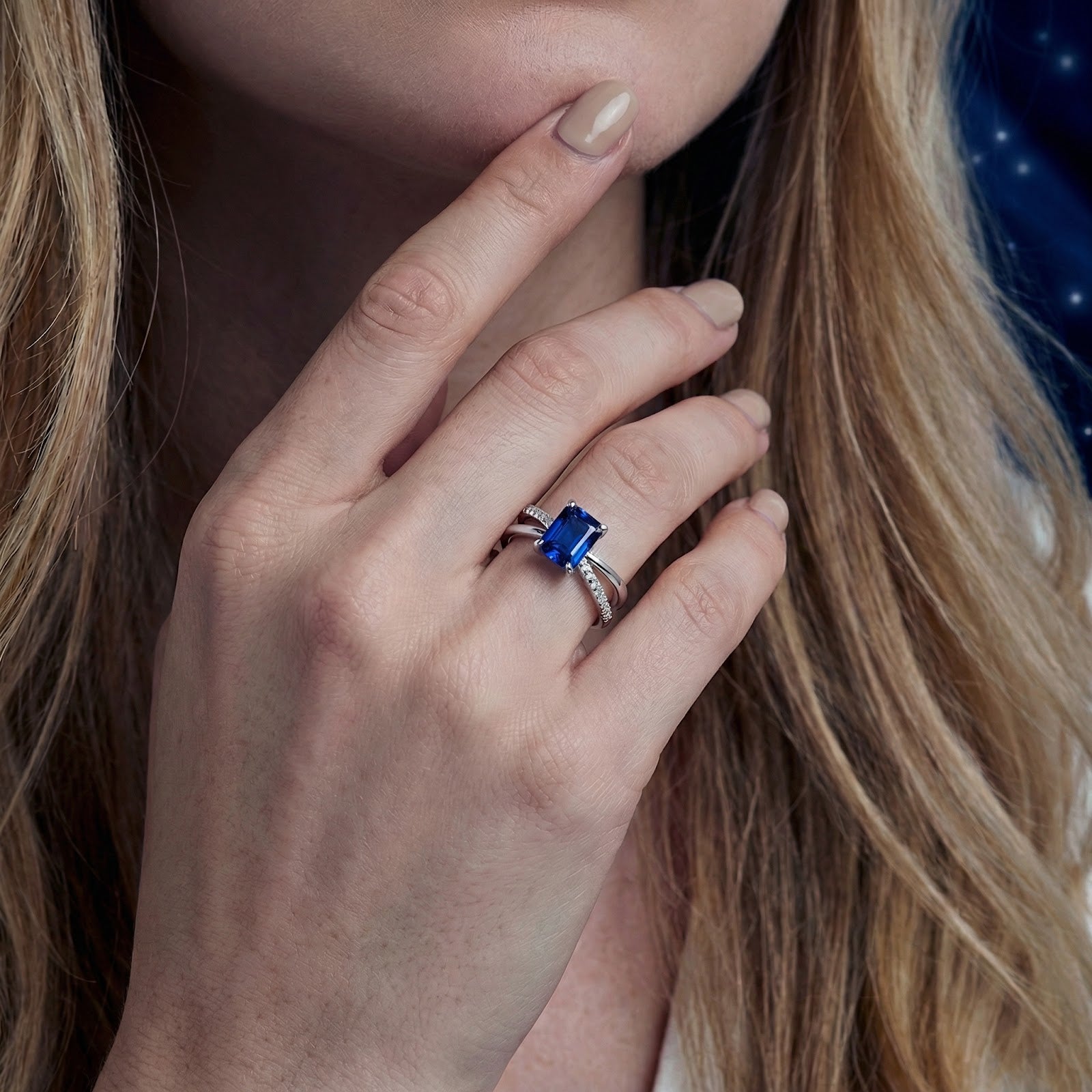 Close-up of the blue simulated sapphire crossover ring in sterling silver worn on a model's hand.