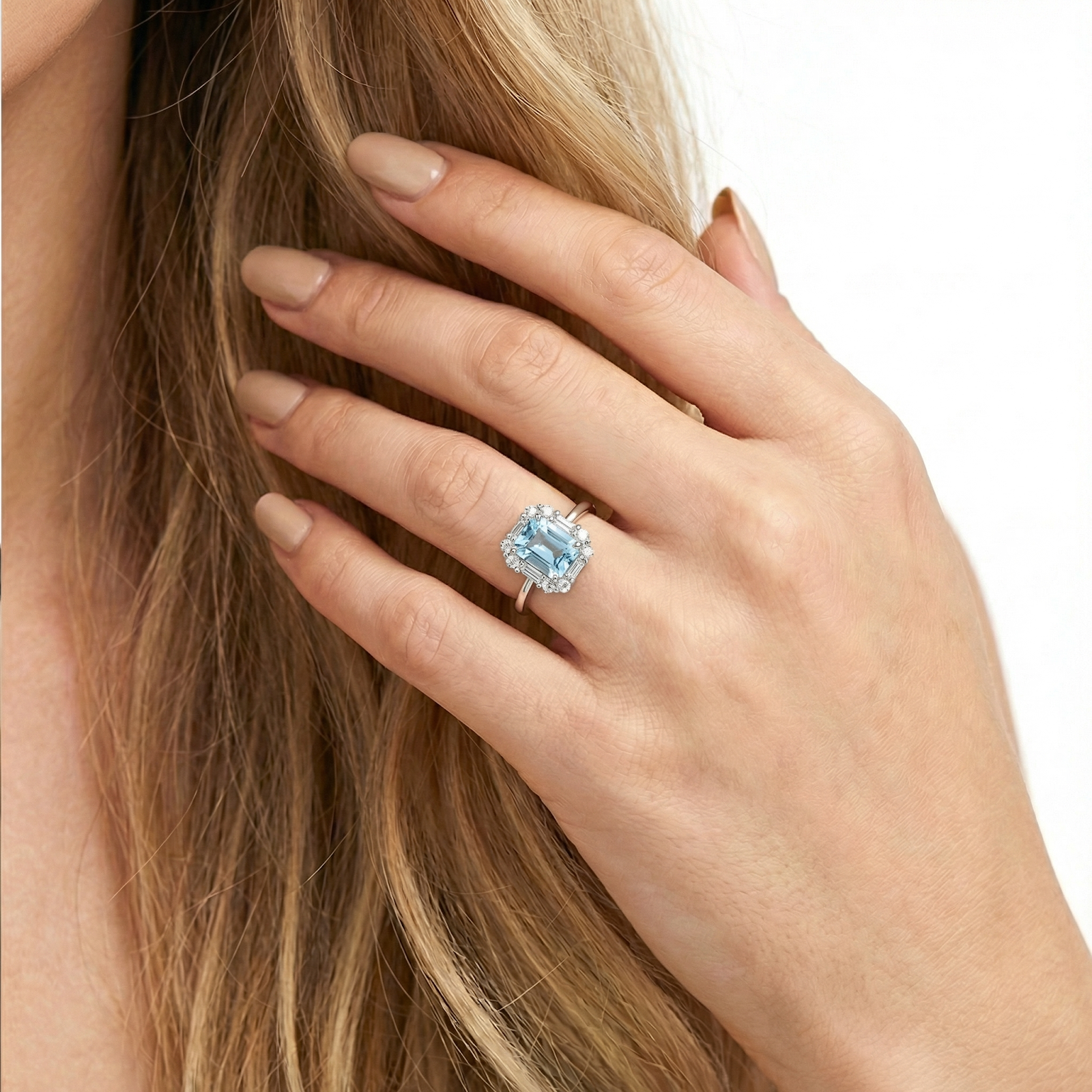 Close-up of a model's hand wearing the sterling silver Linnea halo ring with a light blue octagon center stone.