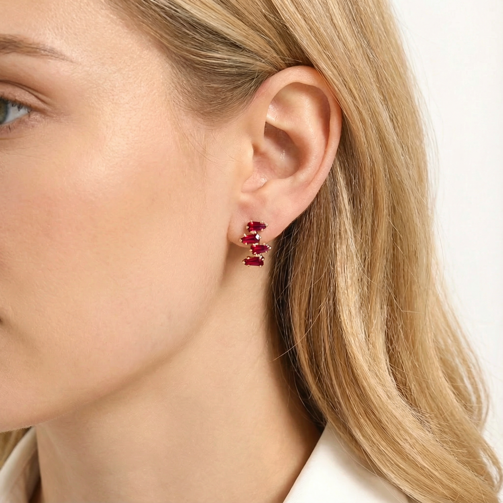 Close-up of the Rhianna Studs in 18K gold vermeil with red simulated rubies worn on a model's ear.
