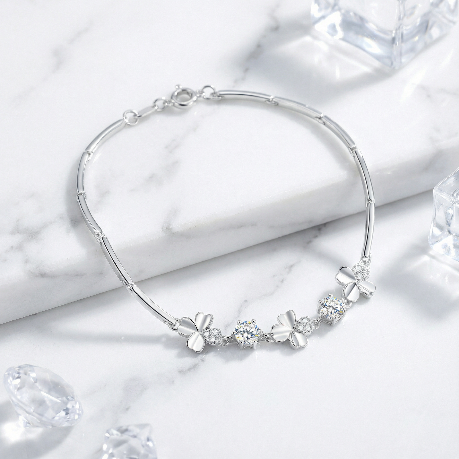 Full view of the silver clover bracelet with round-cut simulated diamonds on marble with decorative ice cubes.