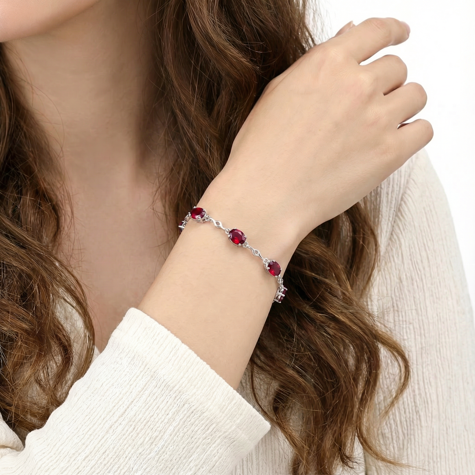 Close-up of the Thalira sterling silver bracelet with oval simulated rubies worn on a model's wrist.