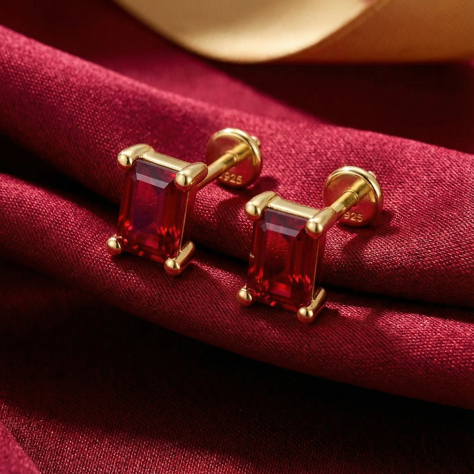 Close-up of emerald-cut pigeon blood simulated ruby earrings in a four-prong 18K gold vermeil setting.