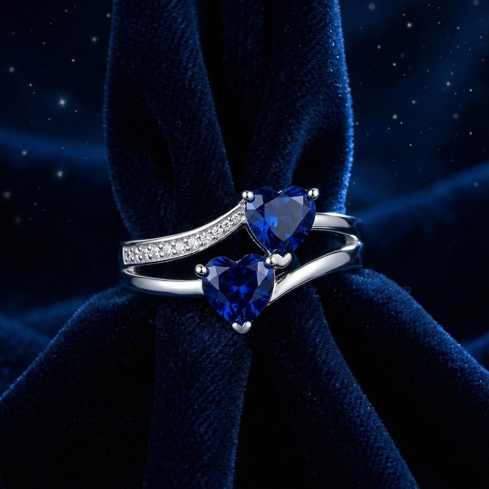 Front view of the sterling silver Marineza heart ring with two blue simulated sapphires on folded blue velvet.