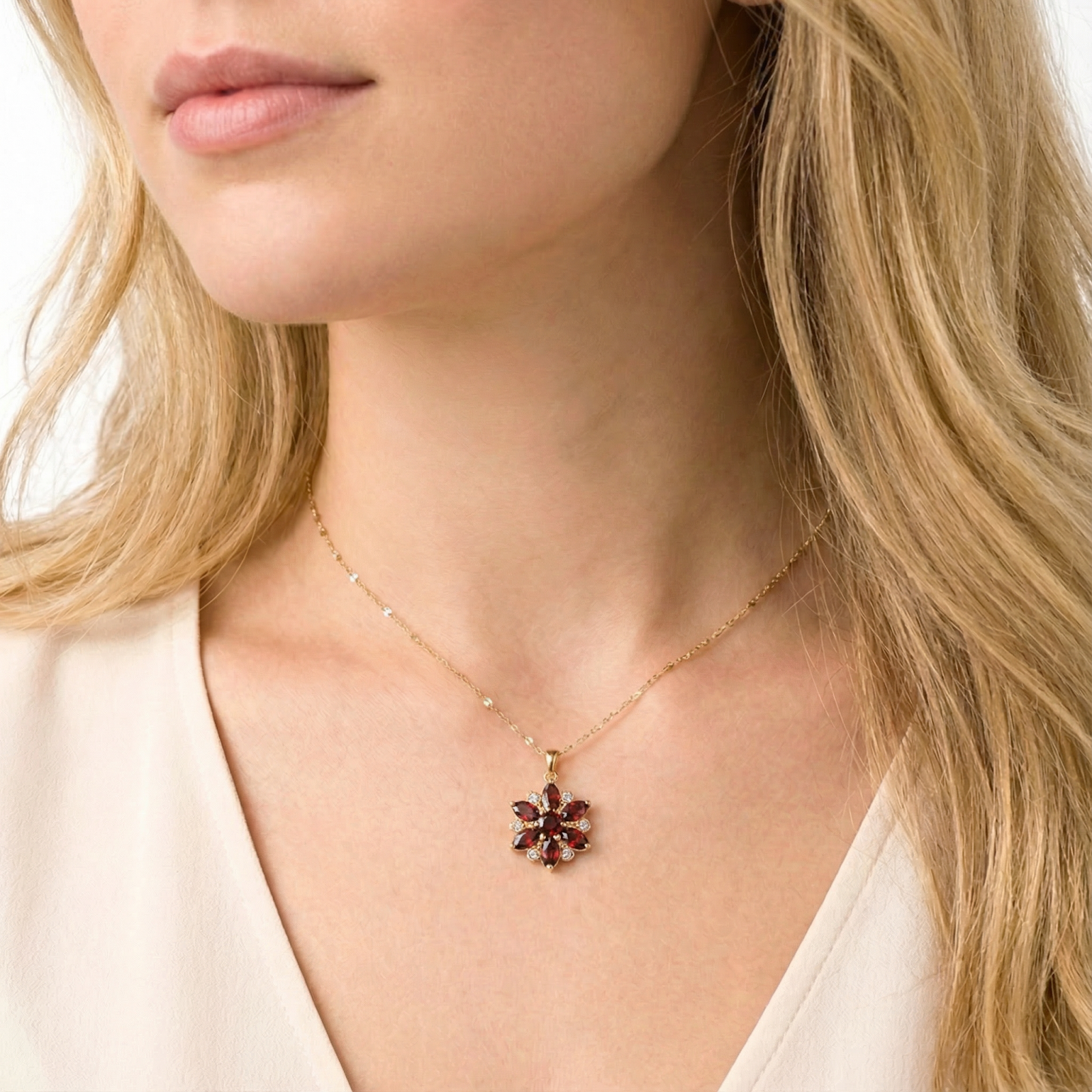 Close-up of a model wearing the gold finished stainless steel Calyx Blossom necklace with red garnets.