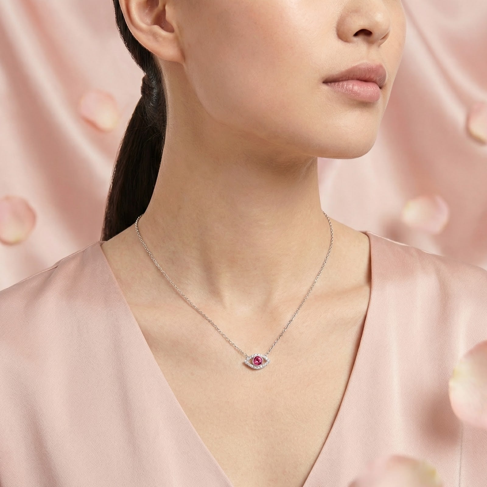 Sterling silver pink moissanite eye necklace worn by a model against a pink backdrop.
