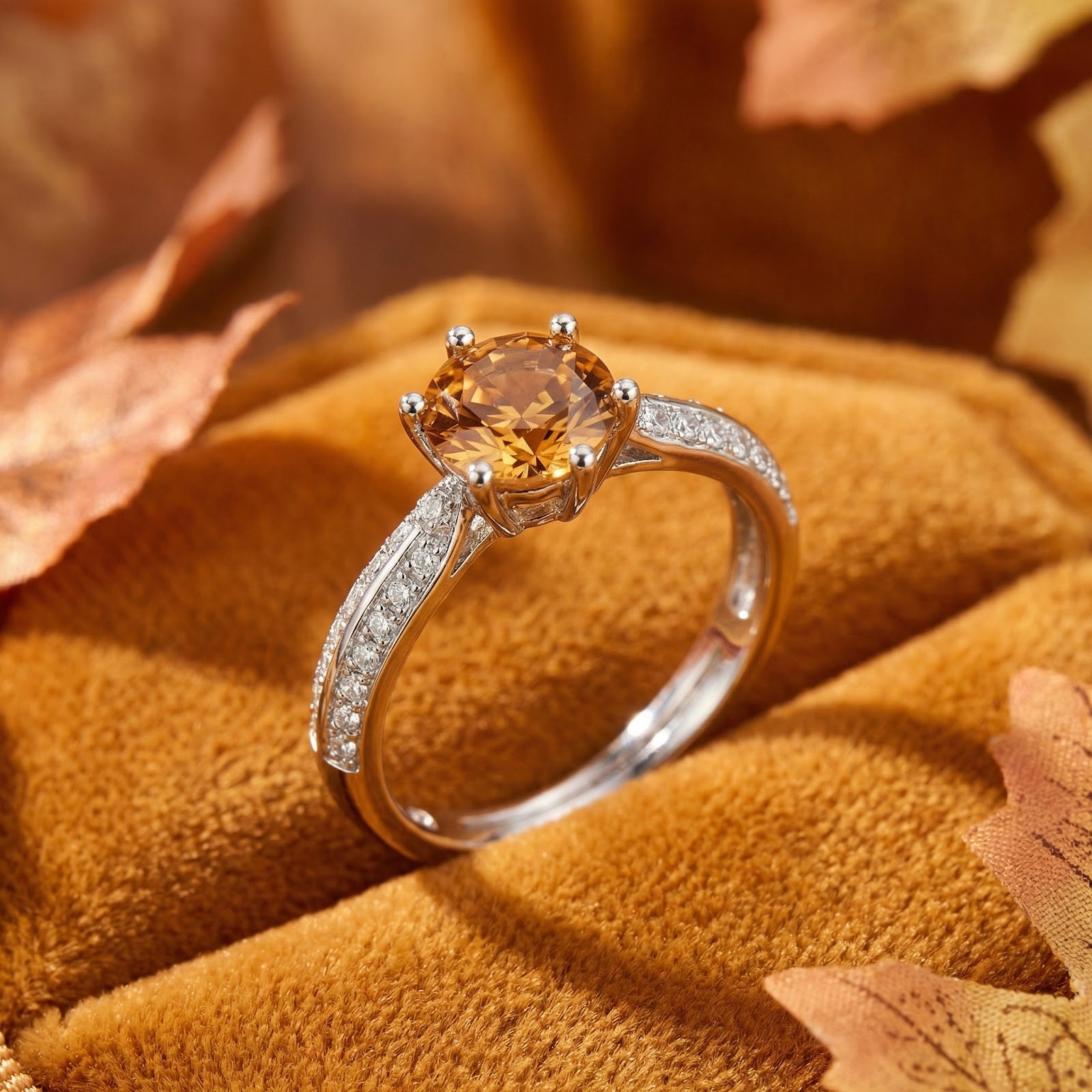 Round cut honeyed simulated topaz ring in sterling silver on a velvet surface with autumn leaves.