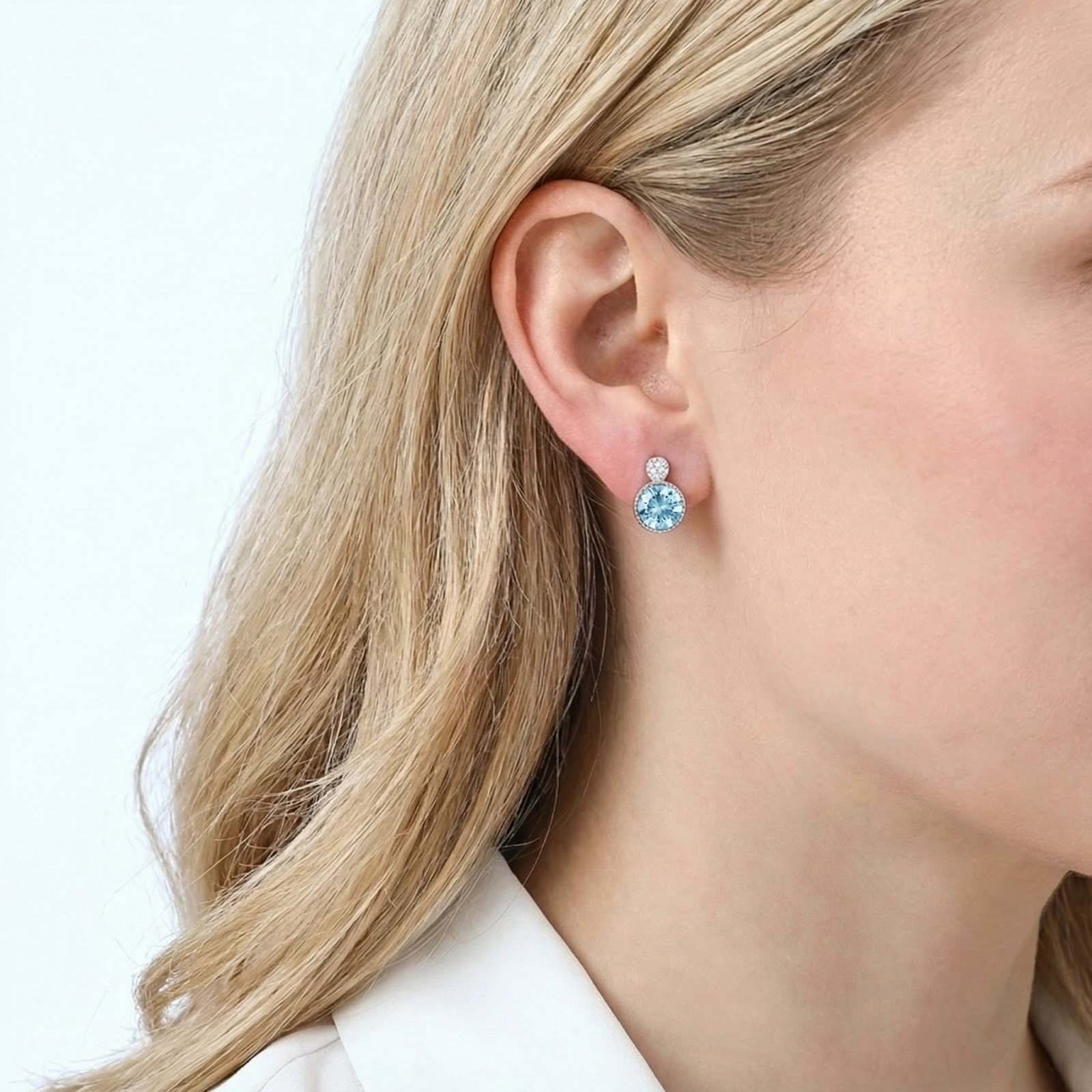 Blonde model wearing a light blue simulated aquamarine stud earring in a sterling silver setting.