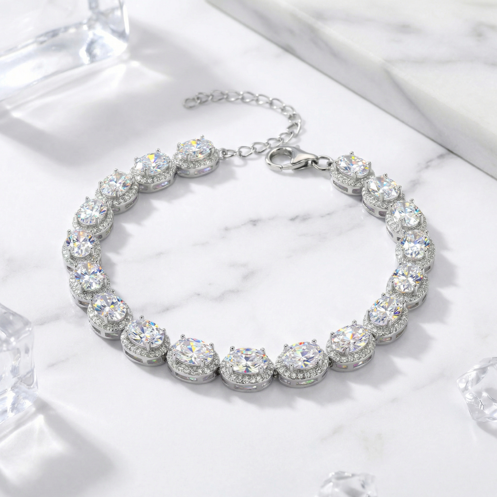 Oval-cut 5A zirconia halo bracelet in S925 sterling silver displayed on a marble surface with decorative ice cubes.