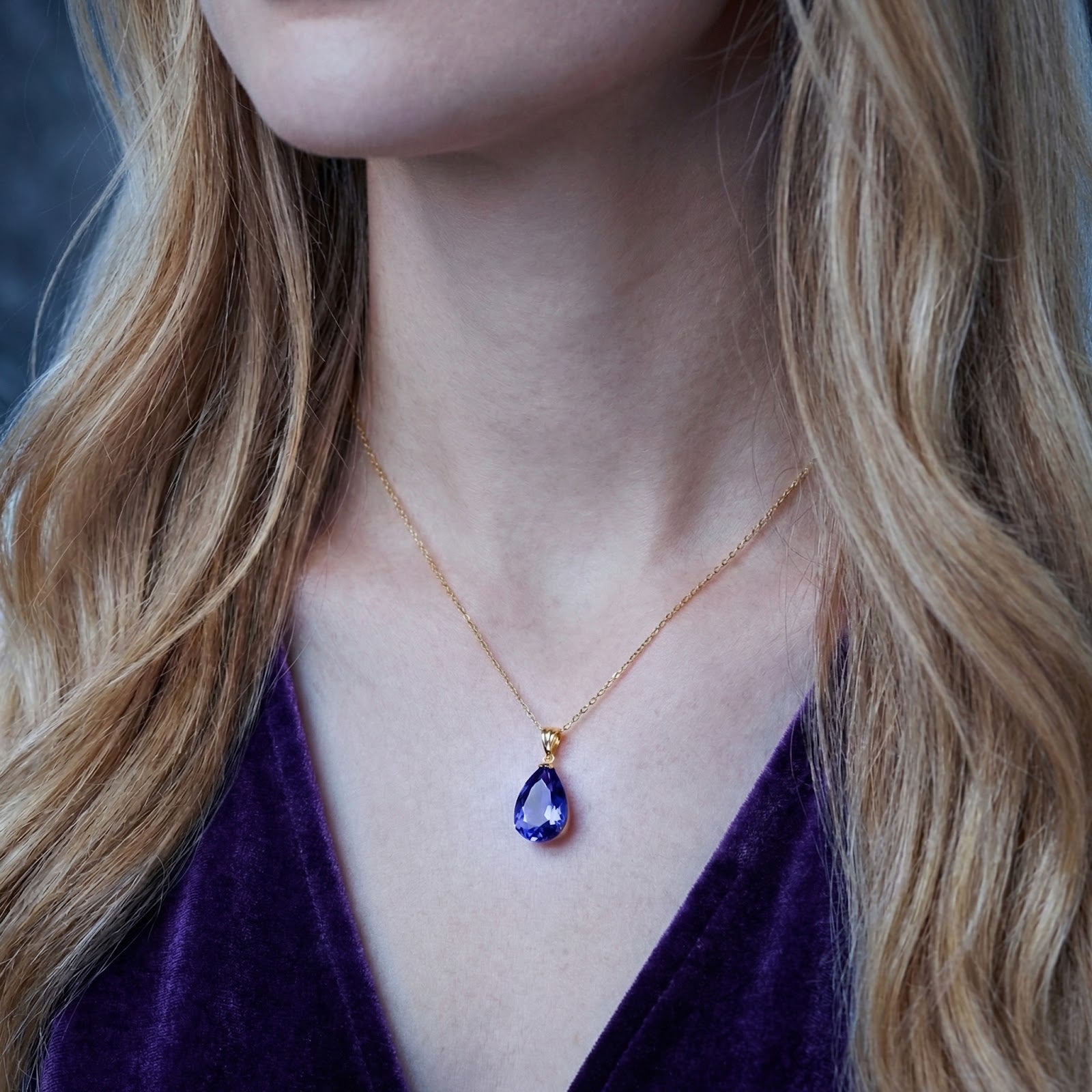Pear-cut simulated tanzanite necklace in 18K gold vermeil worn by a model on a gold chain.