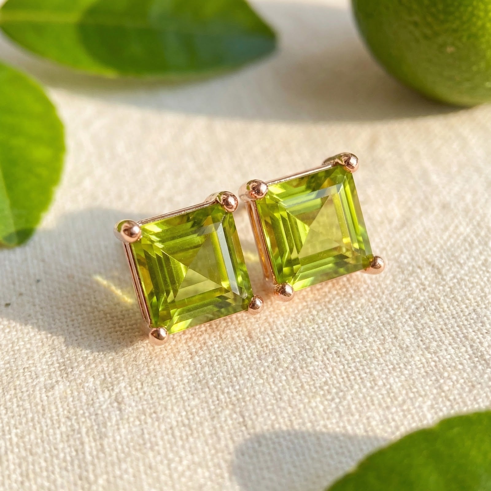 Close-up of square cut simulated peridot earrings in 18K rose gold vermeil settings showing vibrant green clarity.